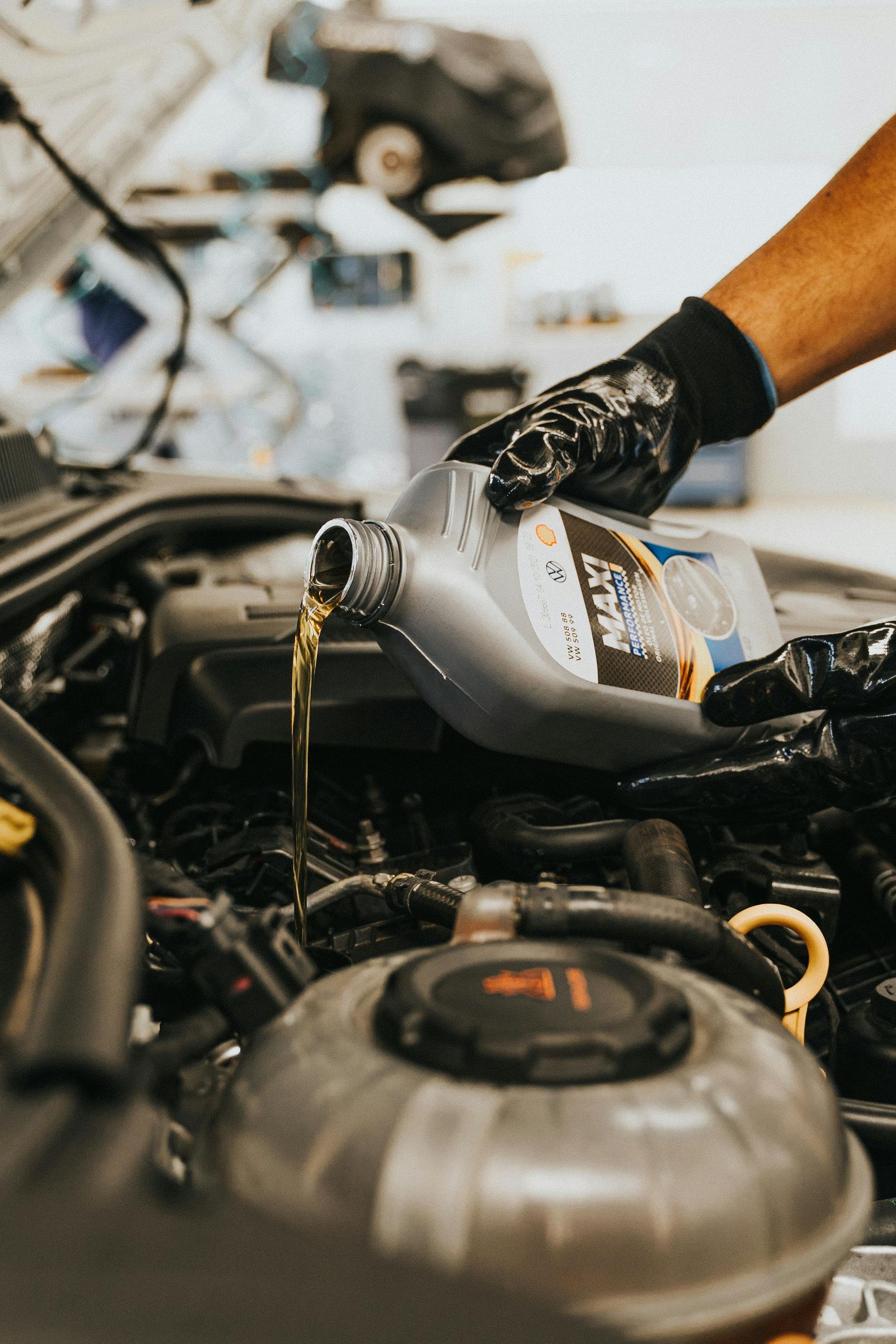A Person Is Pouring Oil Into A Car Engine — Manning Smash & Auto Repairs In Forster, NSW