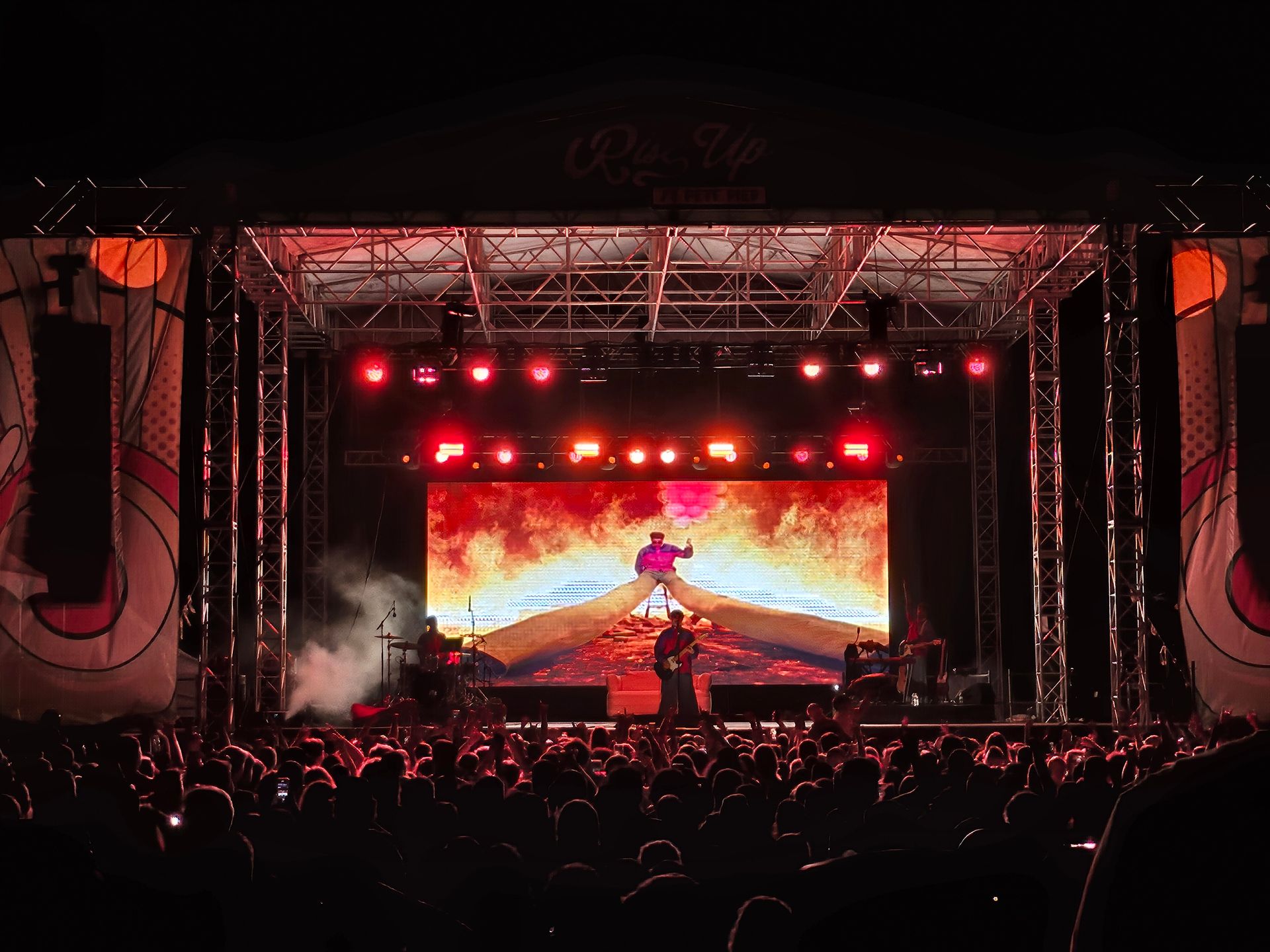 A group of people are standing in front of a stage at a concert.