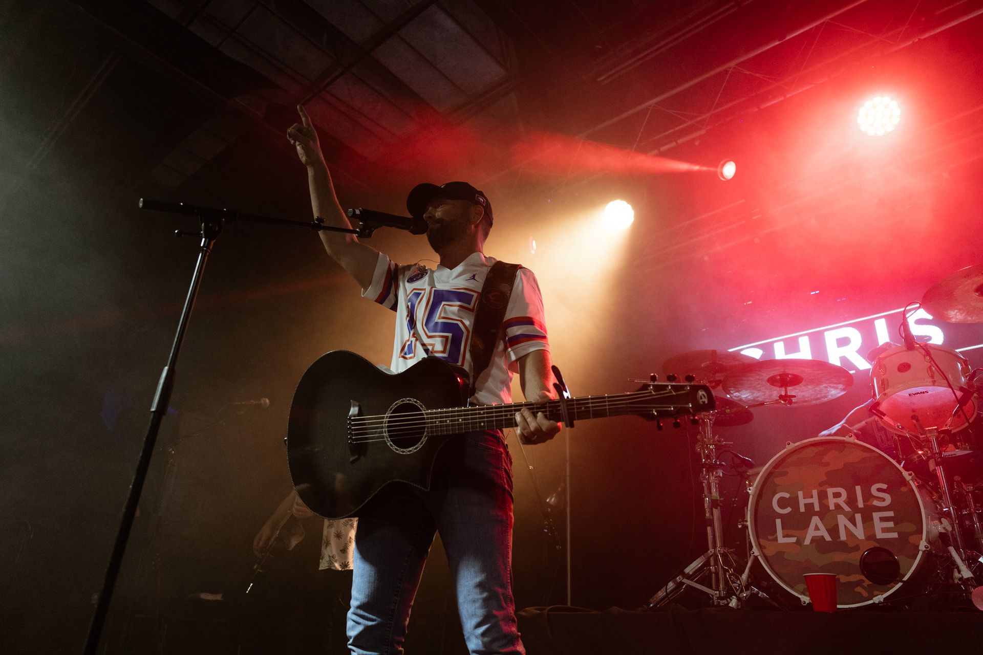 A man is playing a guitar and singing into a microphone on a stage.