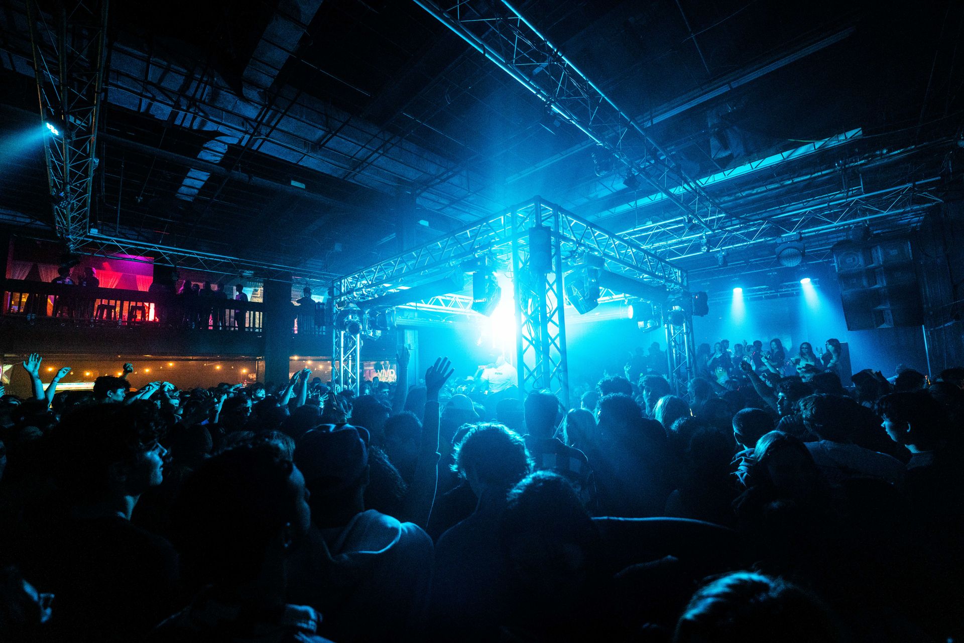 A crowd of people are dancing in a club with blue lights