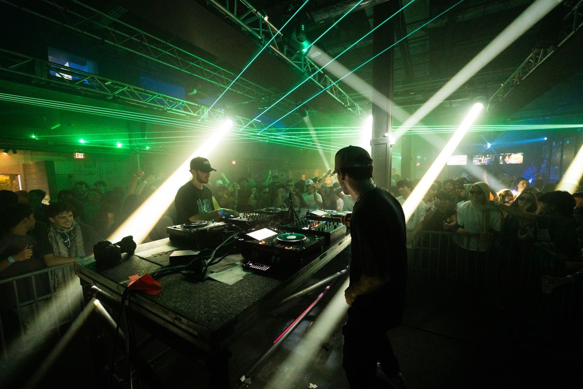 A man is standing in front of a dj booth in a dark room.