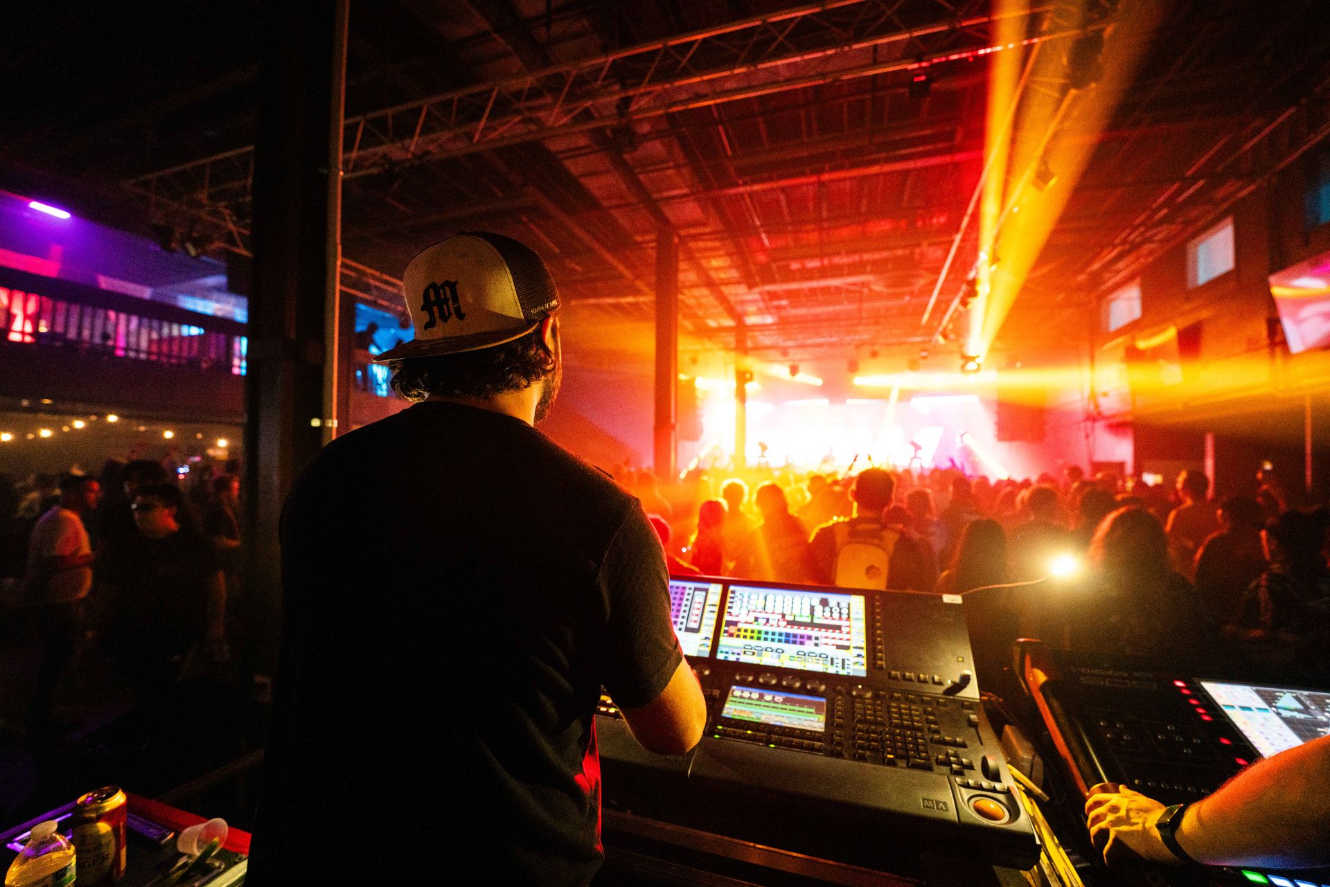 A man is standing in front of a dj booth at a concert.