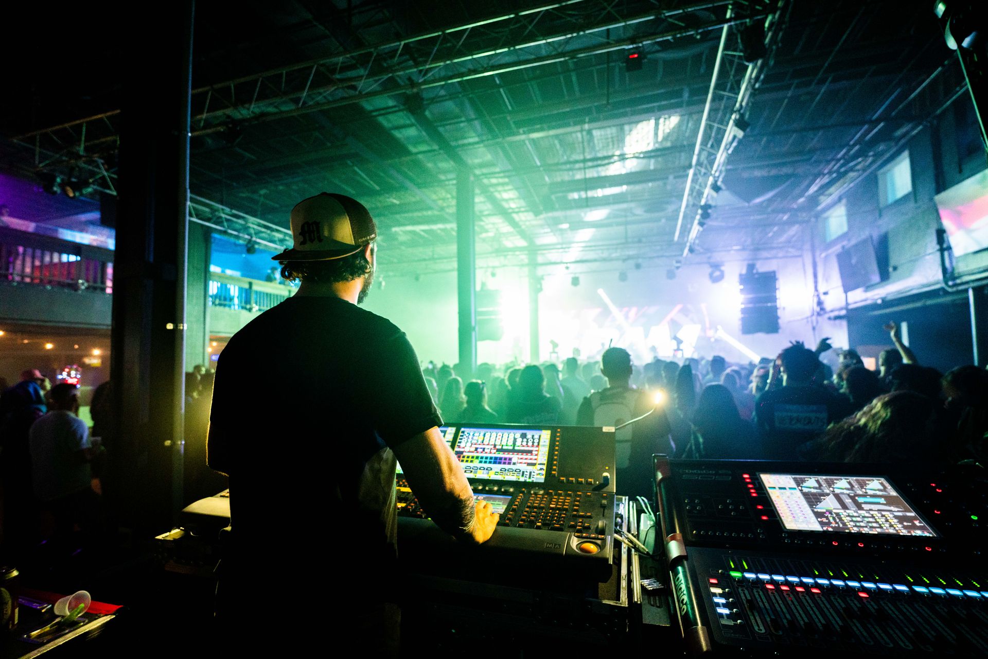 A dj is playing music in front of a crowd at a club.