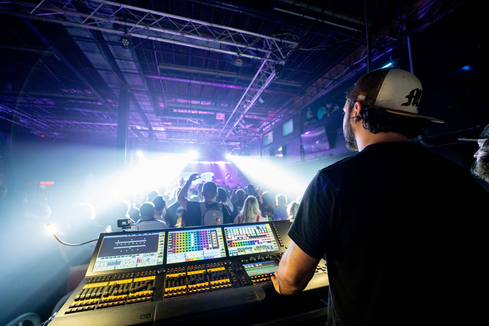 A man is sitting at a desk in front of a crowd at a concert.