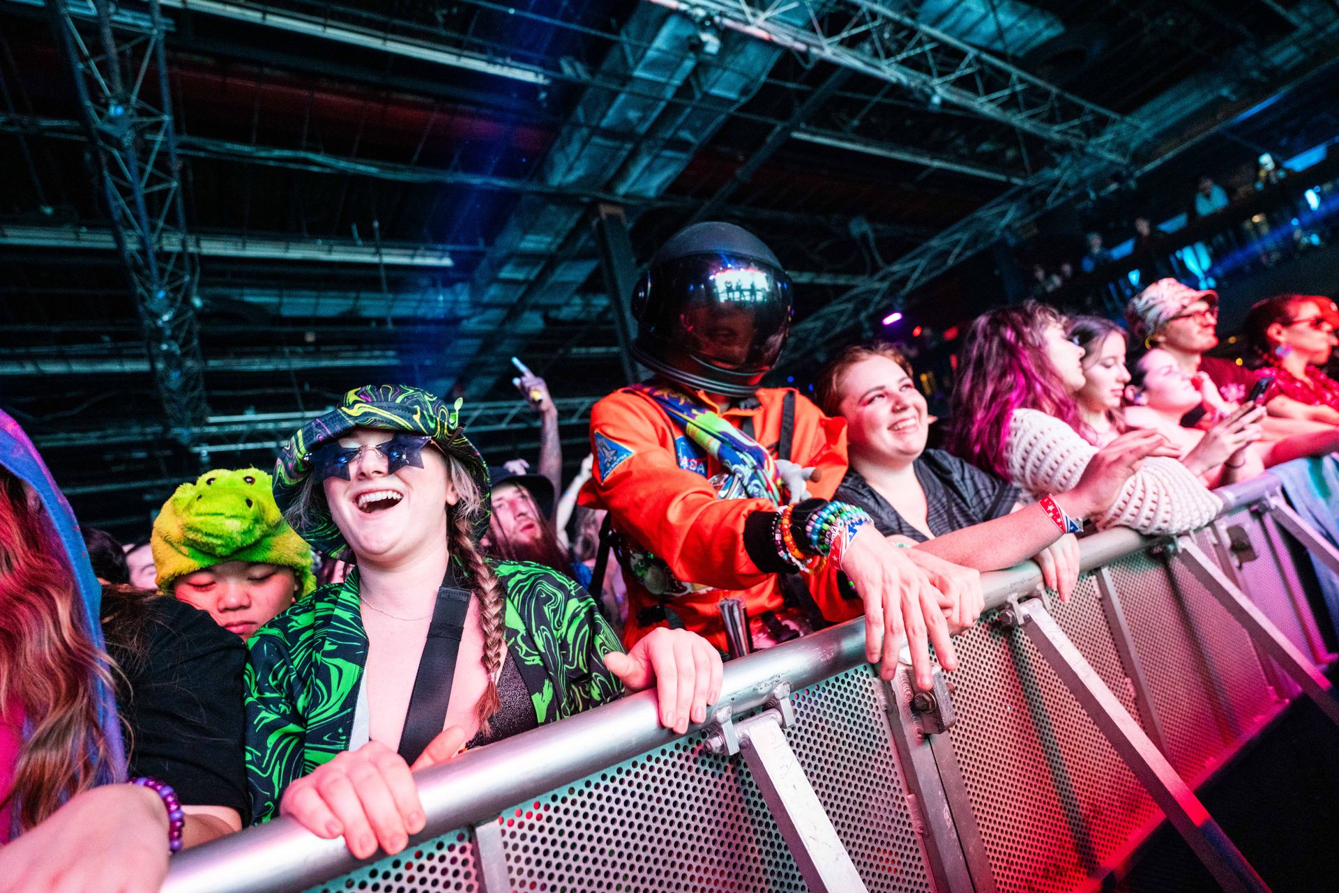 A crowd of people are standing behind a metal barrier at a concert.