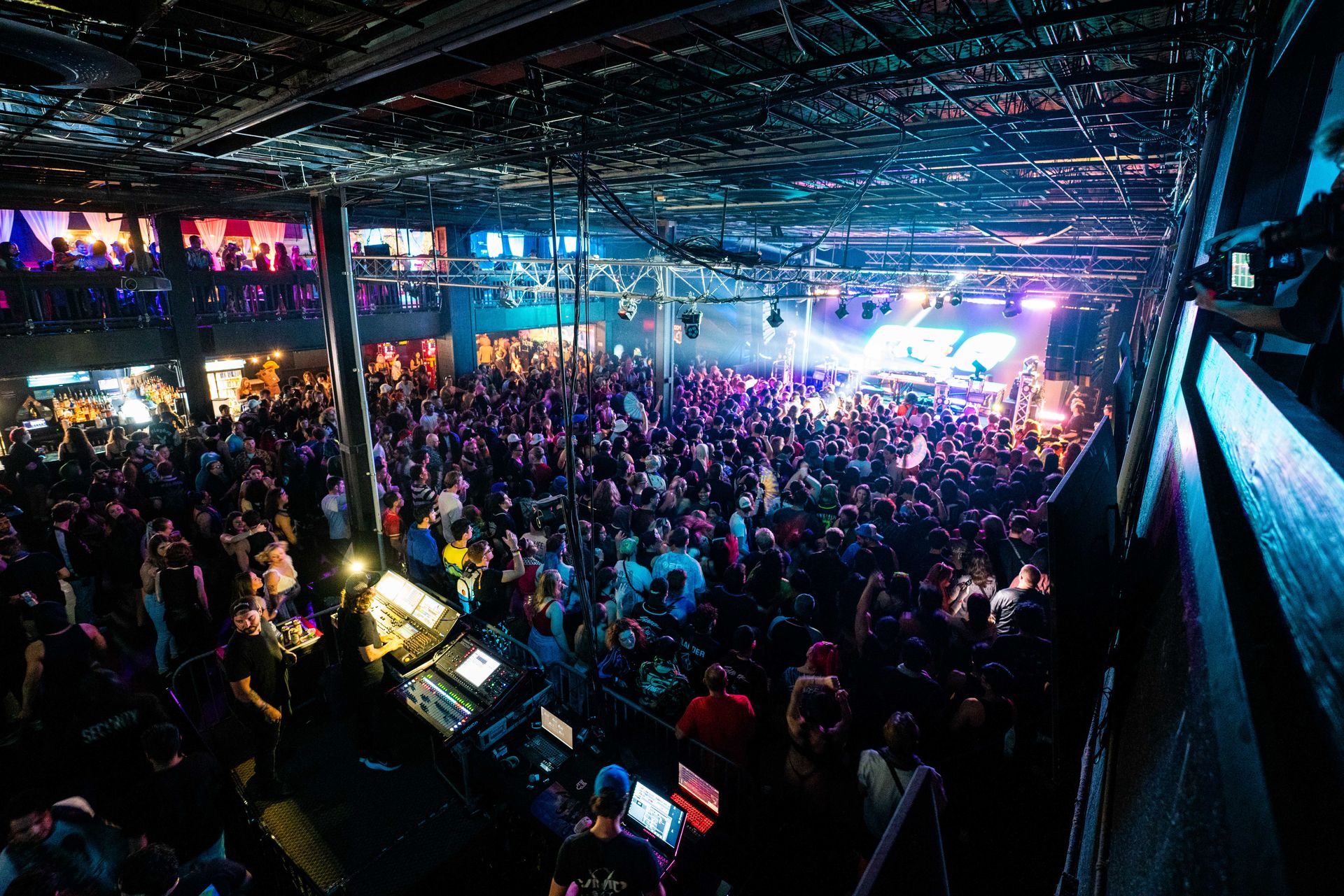 A large crowd of people are gathered in a large room at a concert.