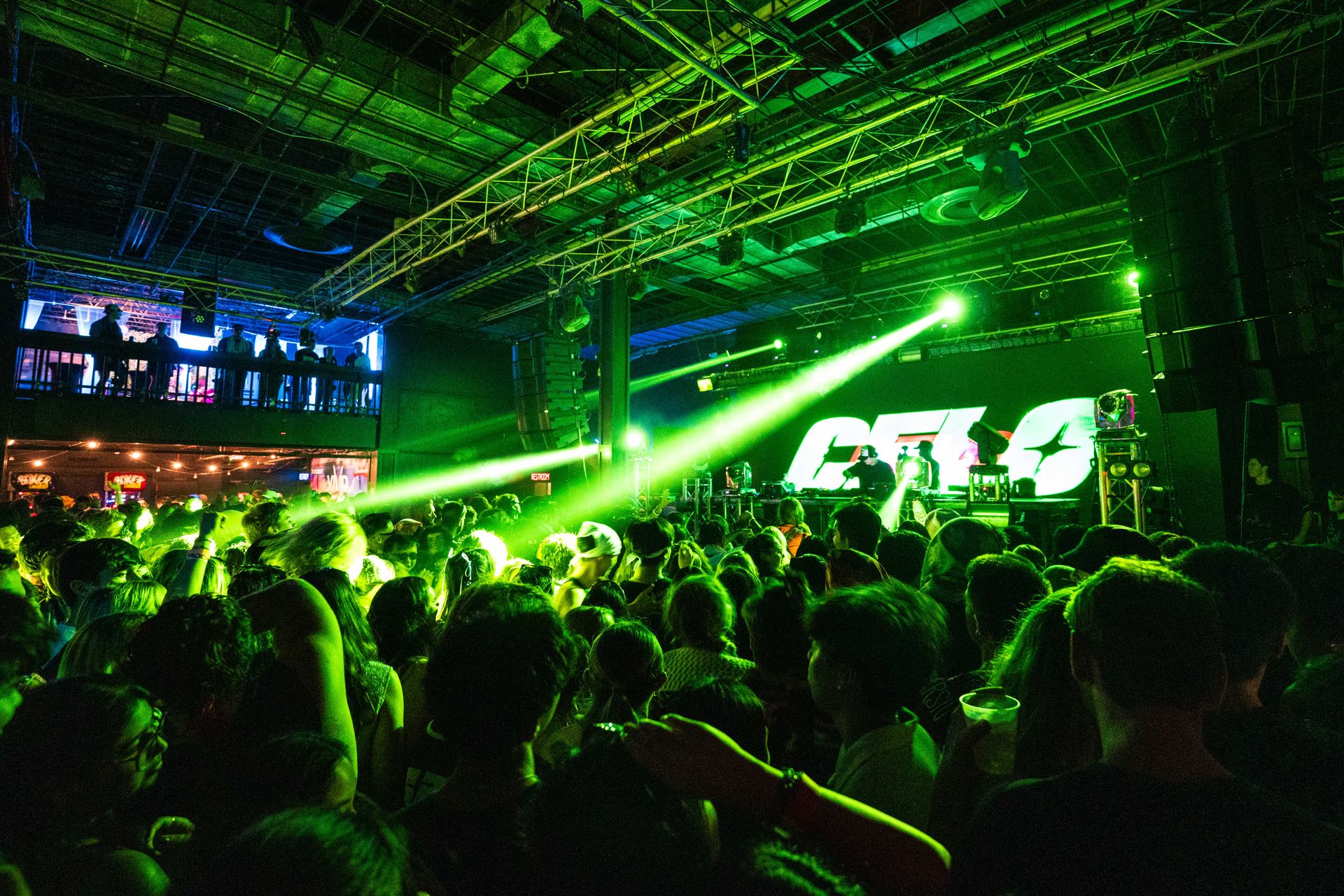 A crowd of people are gathered in a club with a green sign that says ctla