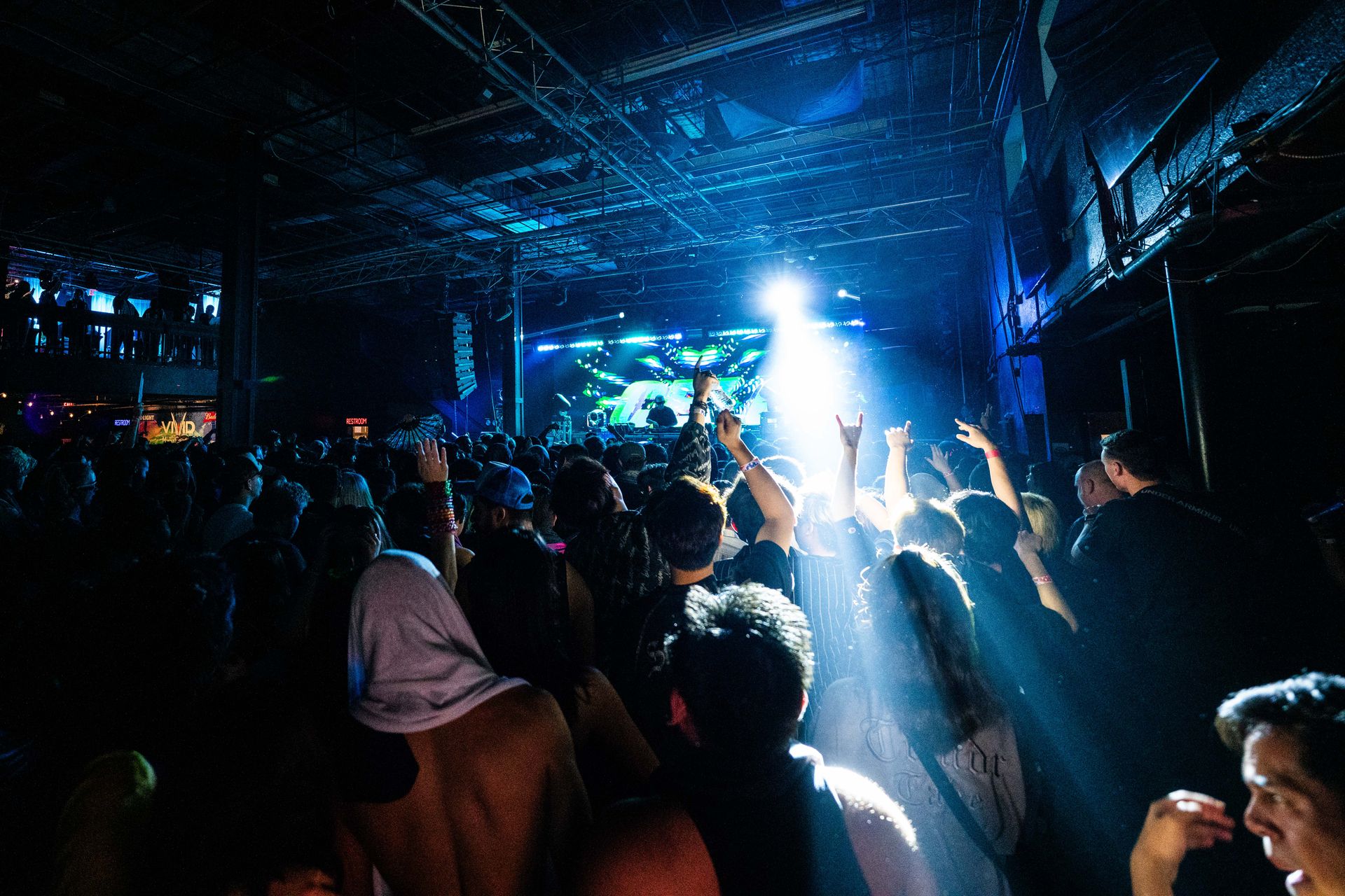 A crowd of people are standing in front of a stage at a concert.