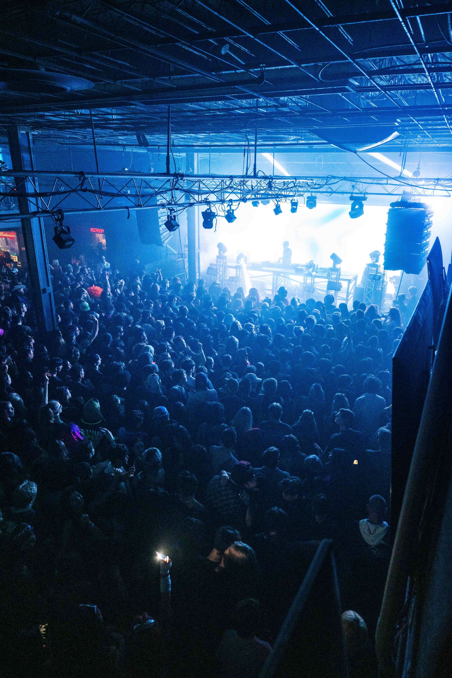 A crowd of people are gathered in a dark room at a concert