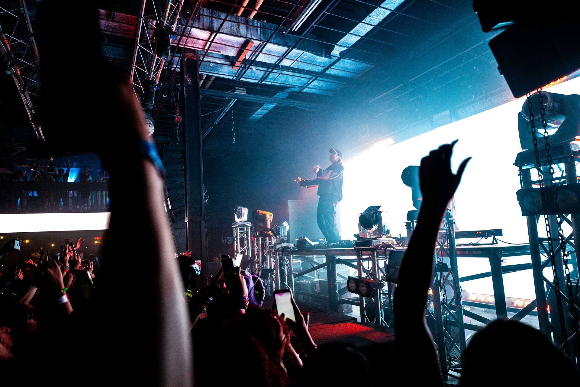 A crowd of people are watching a concert with their hands in the air.