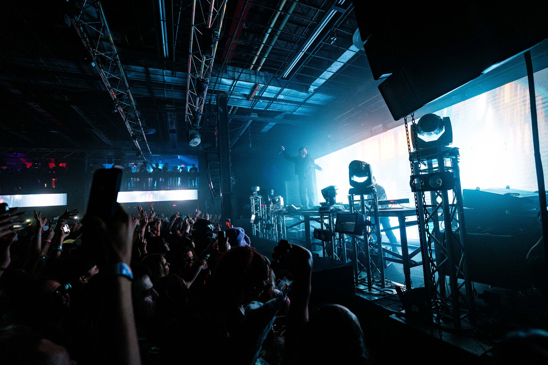 A crowd of people are standing in front of a stage at a concert.