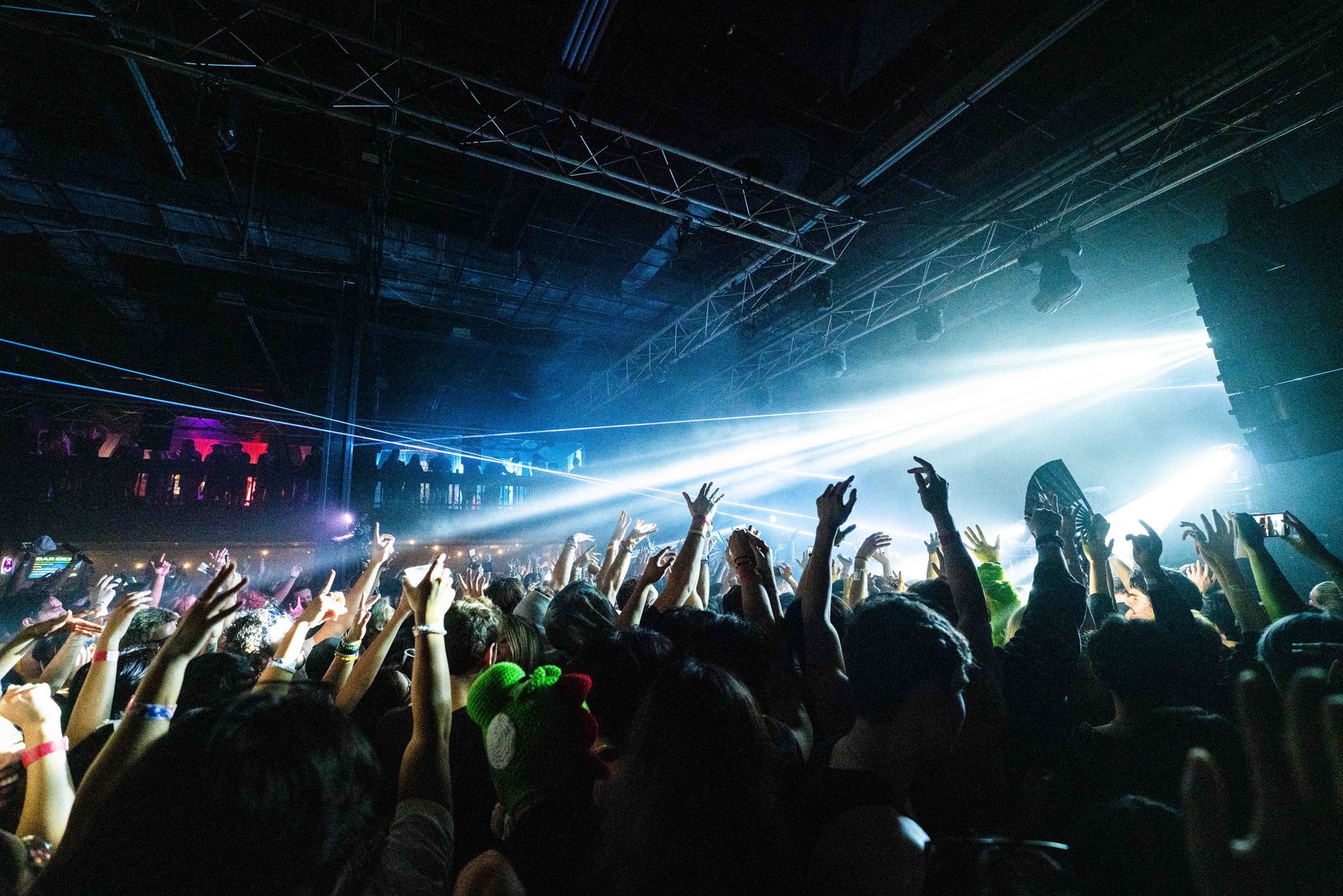 A crowd of people are raising their hands in the air at a concert.