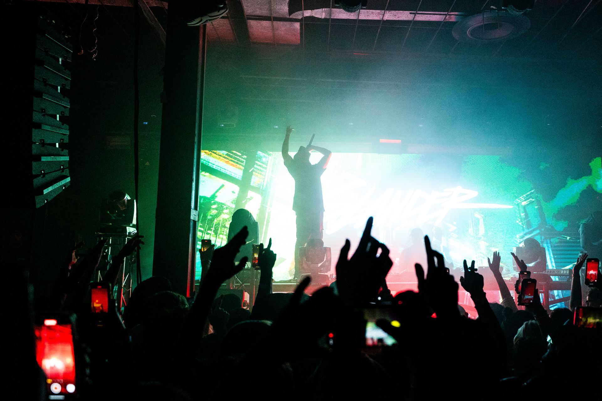 A group of people are standing in front of a stage with their hands in the air.