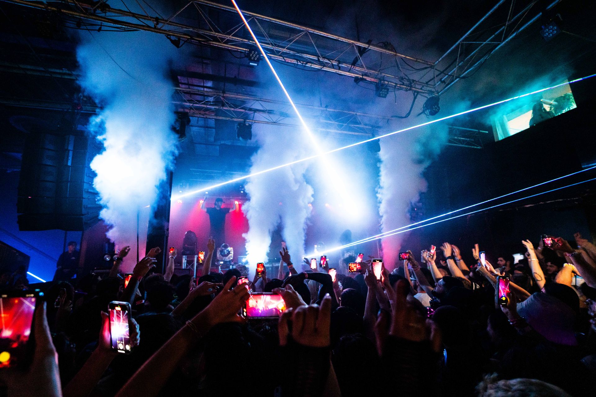 A crowd of people are standing in front of a stage at a concert.