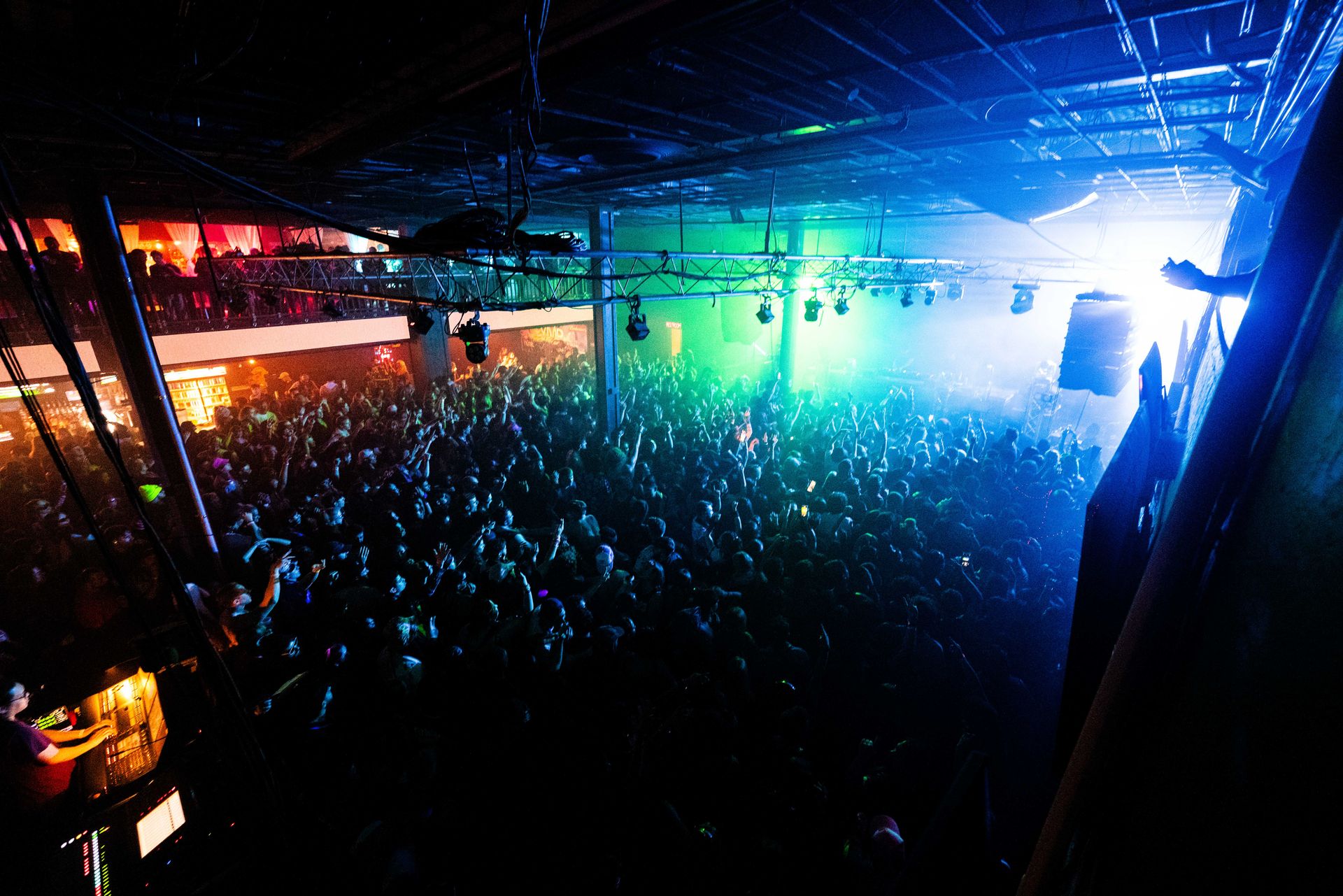 A large crowd of people are gathered in a dark room at a concert.