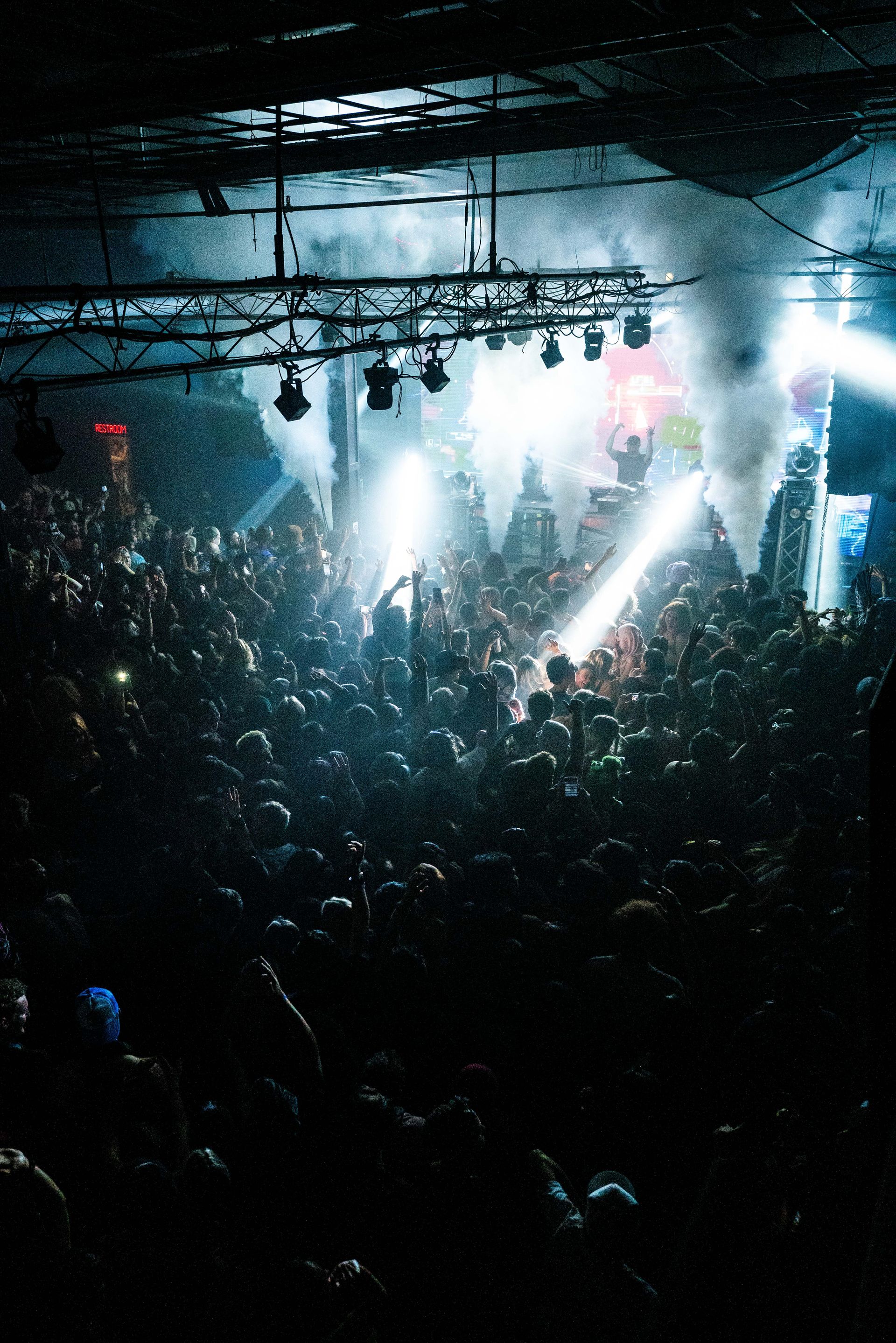 A crowd of people are watching a concert in a dark room.