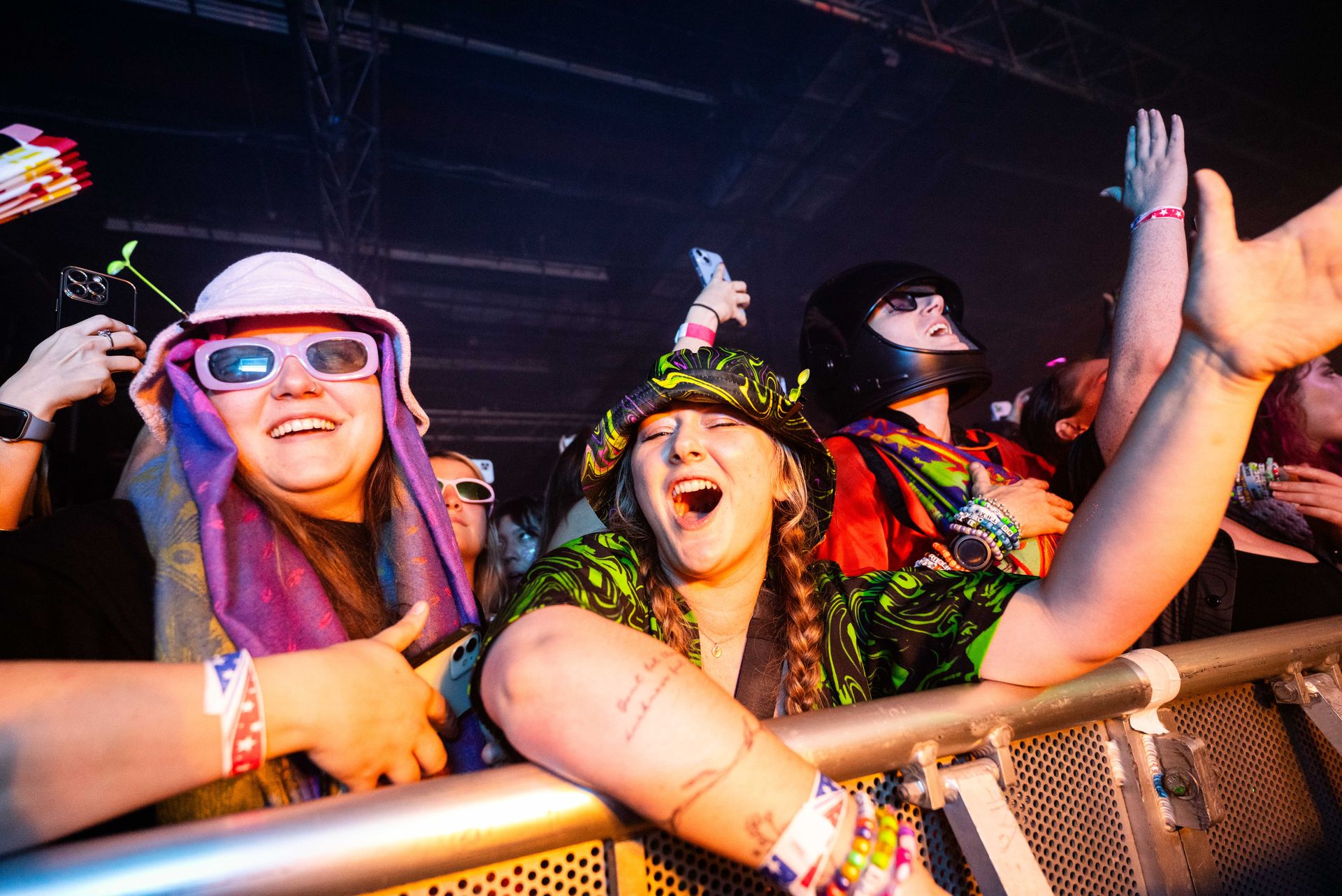 A group of people are standing behind a fence at a concert.