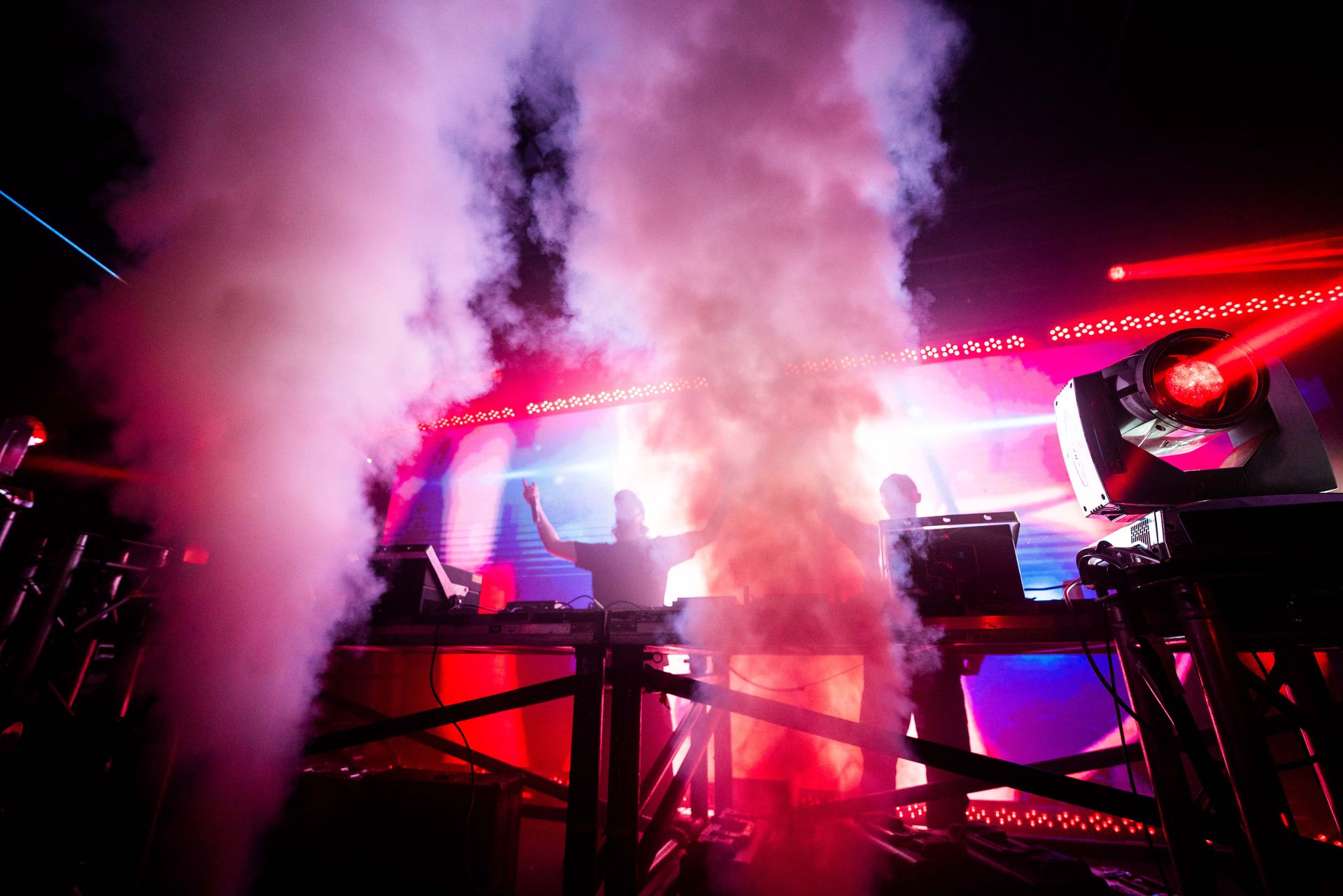 A couple of people standing on a stage with smoke coming out of them.