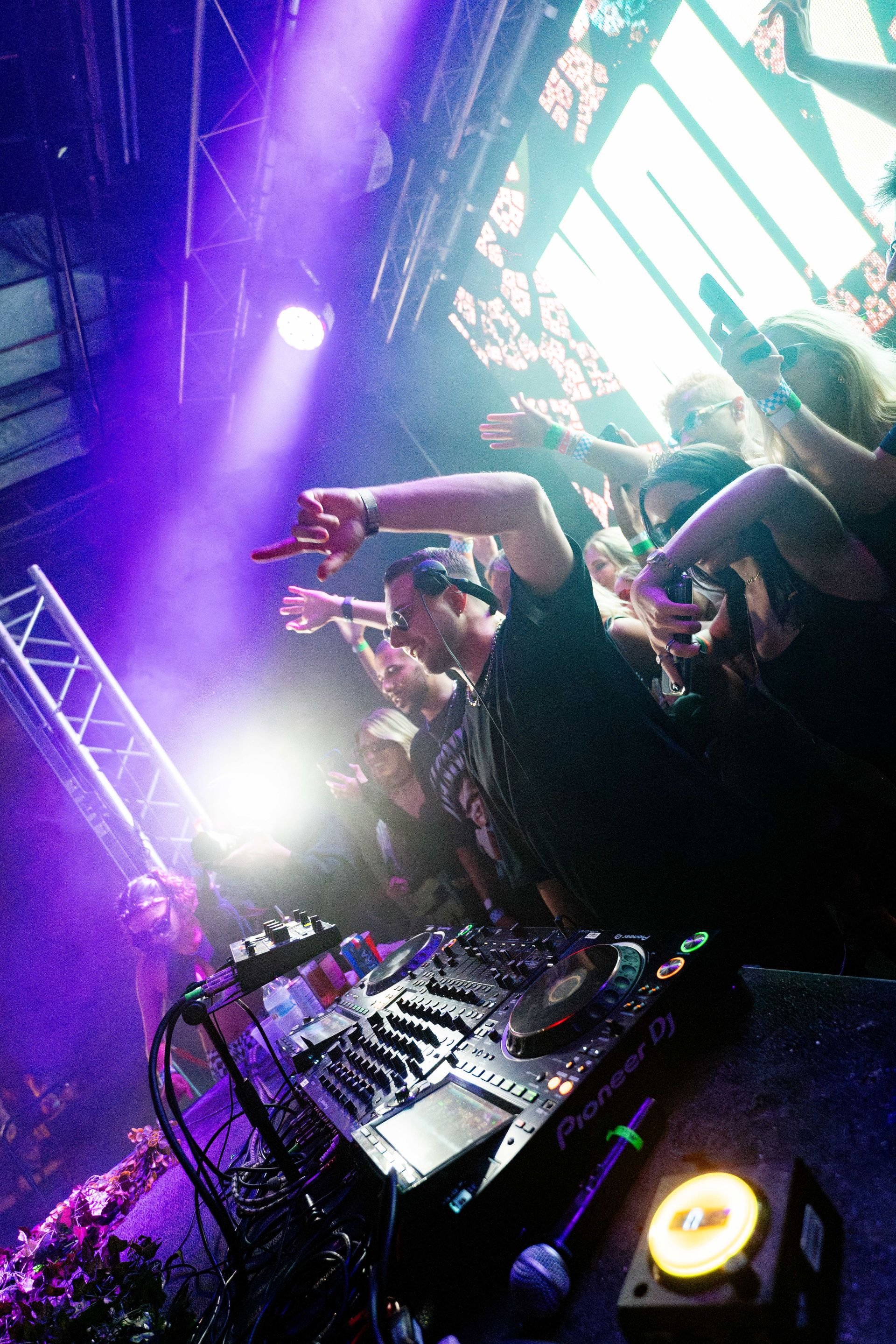 A dj is playing music in front of a crowd at a concert.