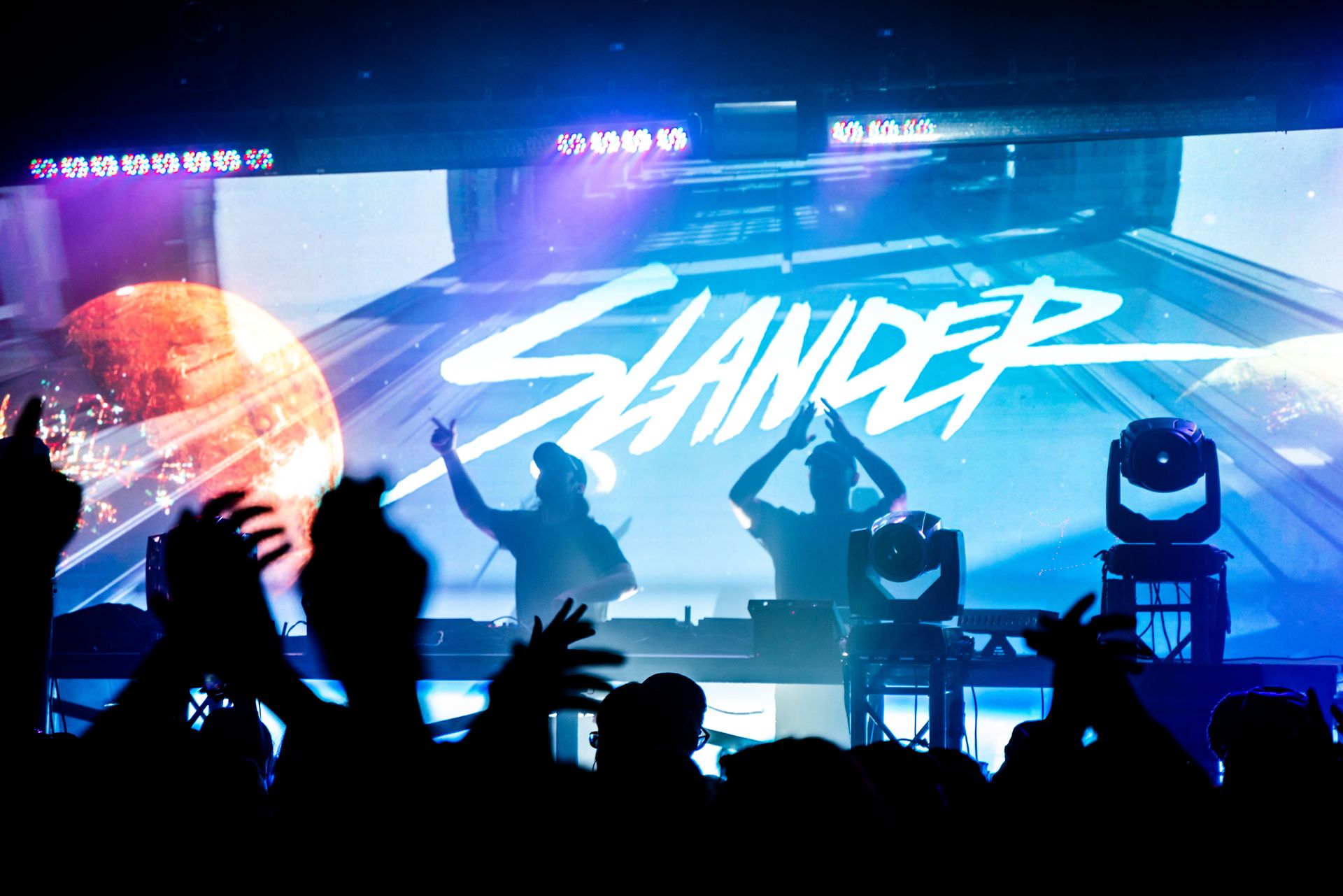 A group of people are standing in front of a stage with the word slander on it.