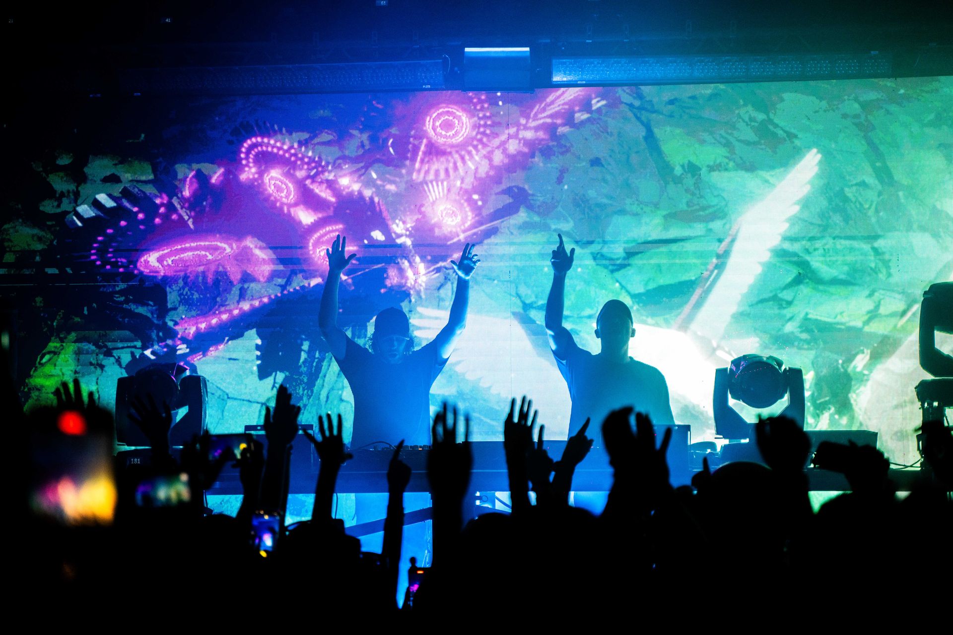A group of people are standing in front of a stage with their hands in the air.