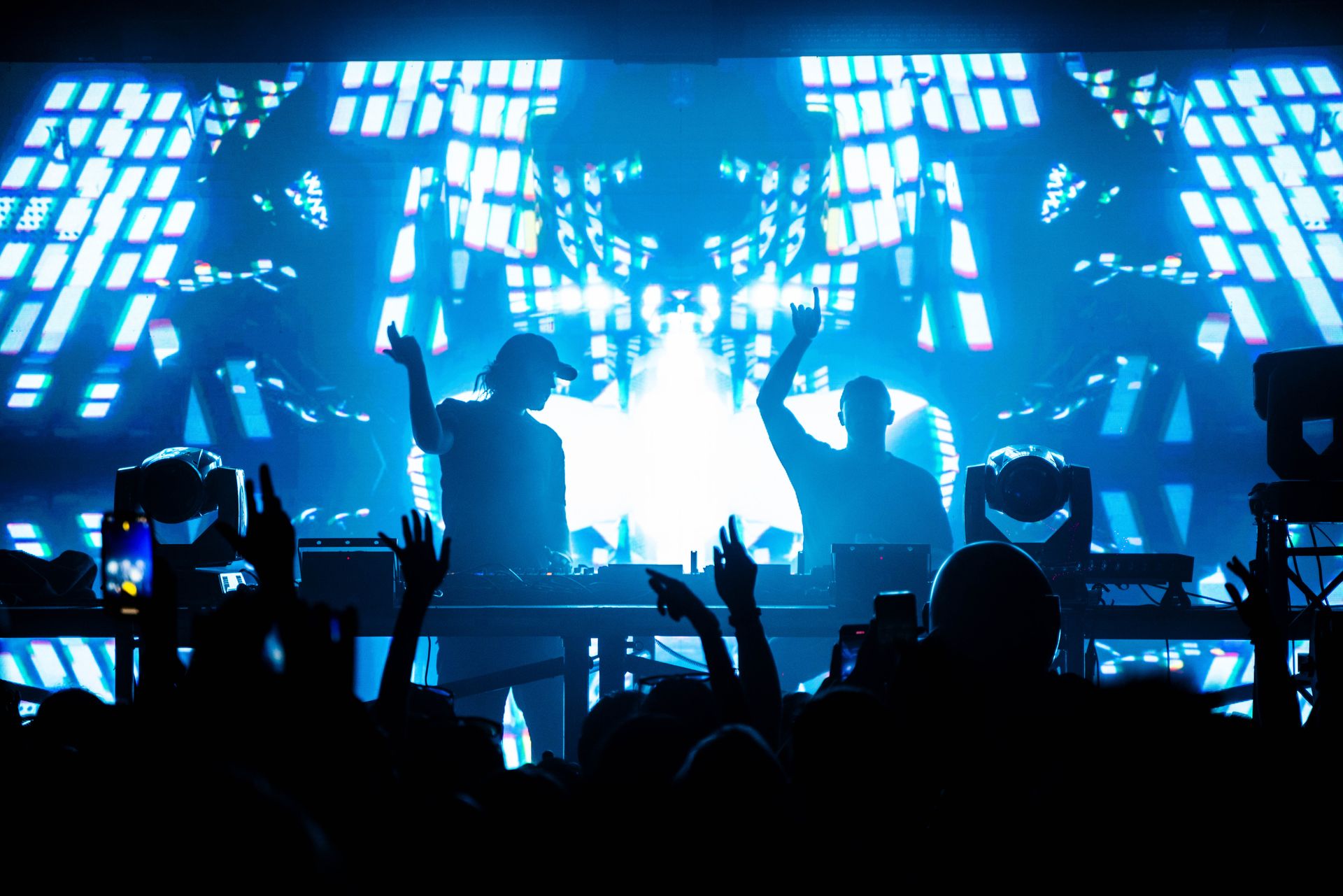 A crowd of people at a concert with their hands in the air