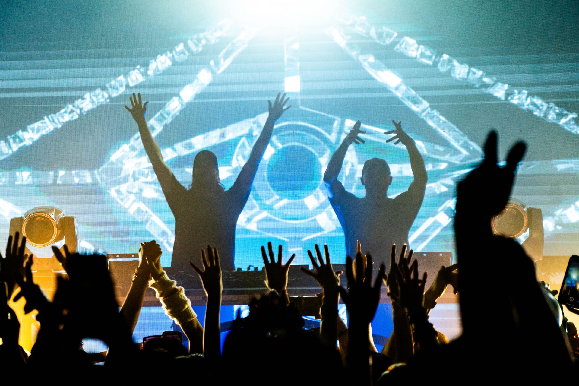 A crowd of people are raising their hands in the air at a concert.