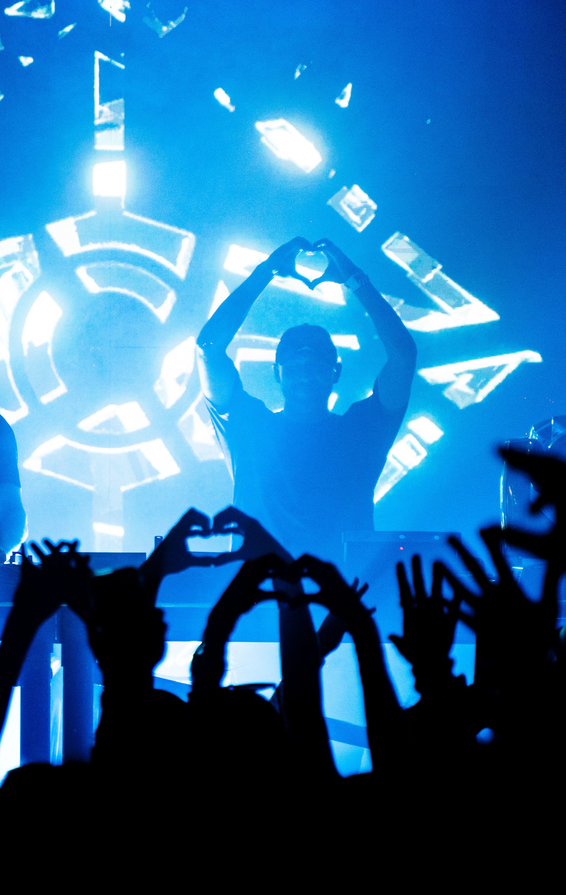 A man making a heart shape with his hands in front of a crowd