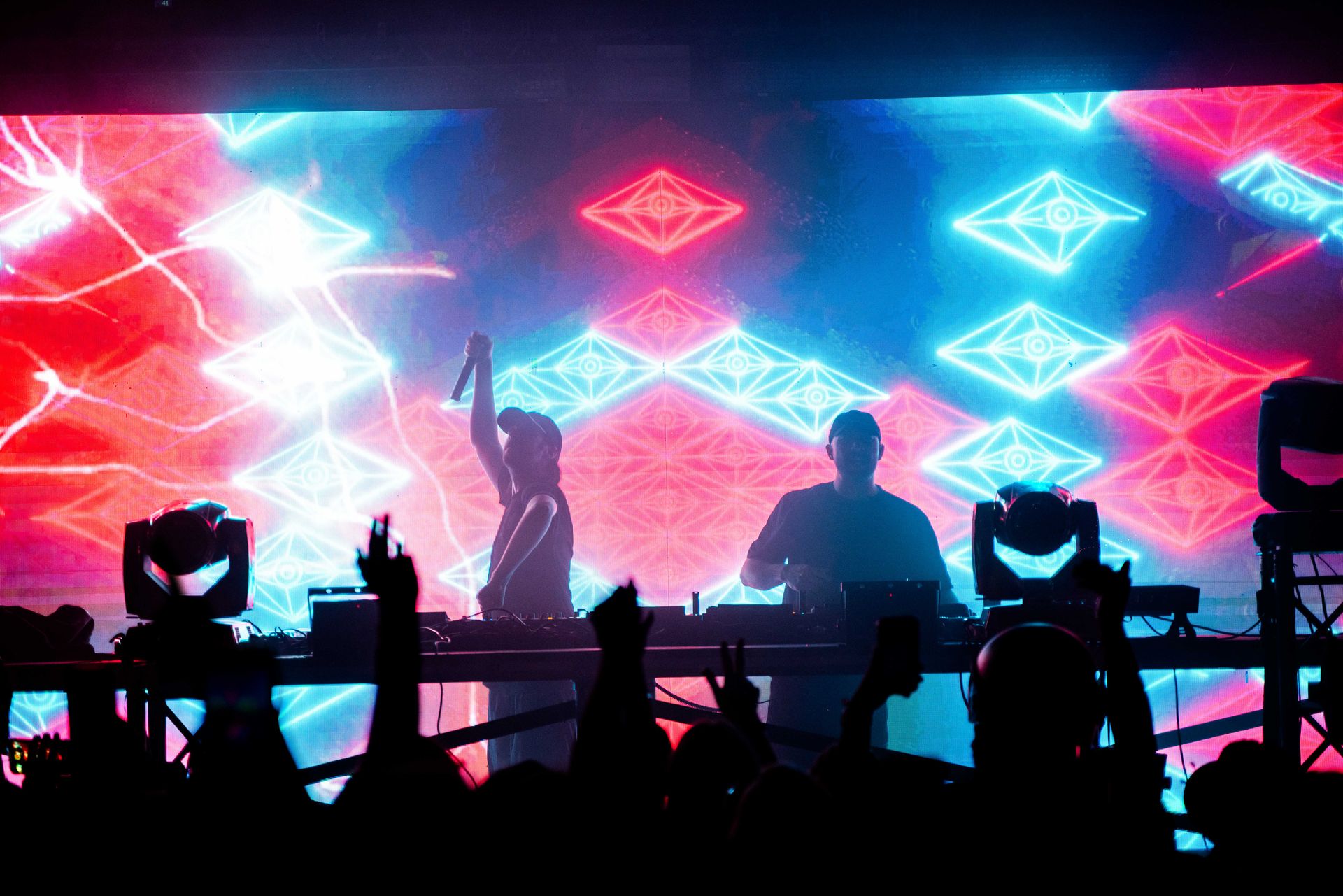 Two dj 's are playing music in front of a crowd at a concert.