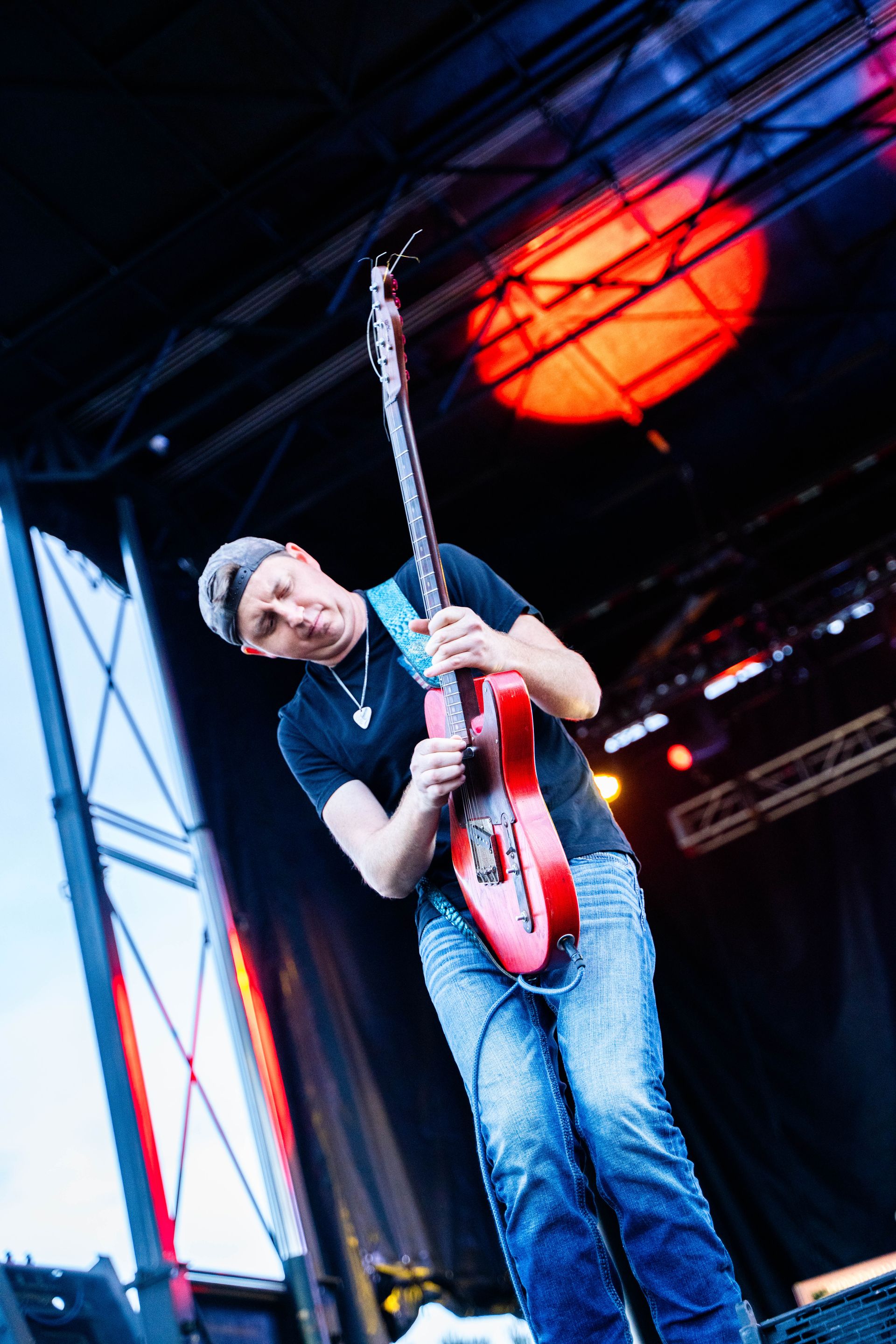 A man is playing a red guitar on a stage