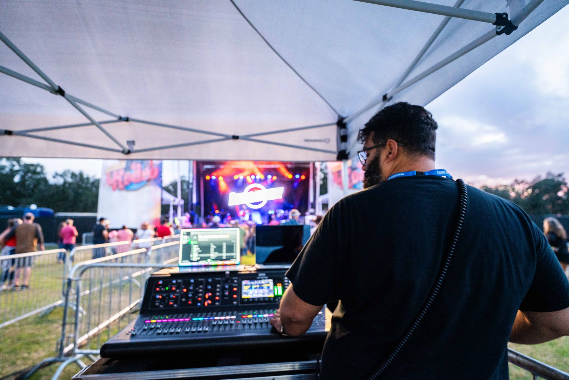A man is sitting in front of a mixer at a concert.