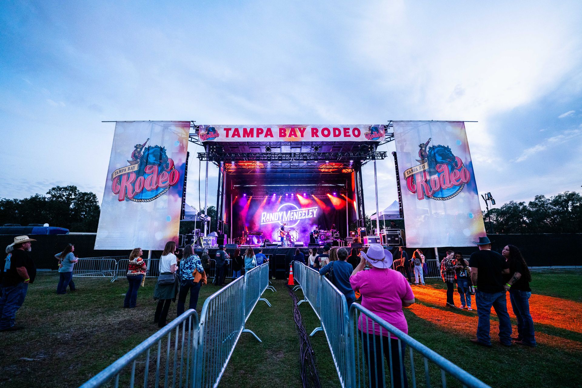 A group of people are standing in front of a stage at a rodeo.