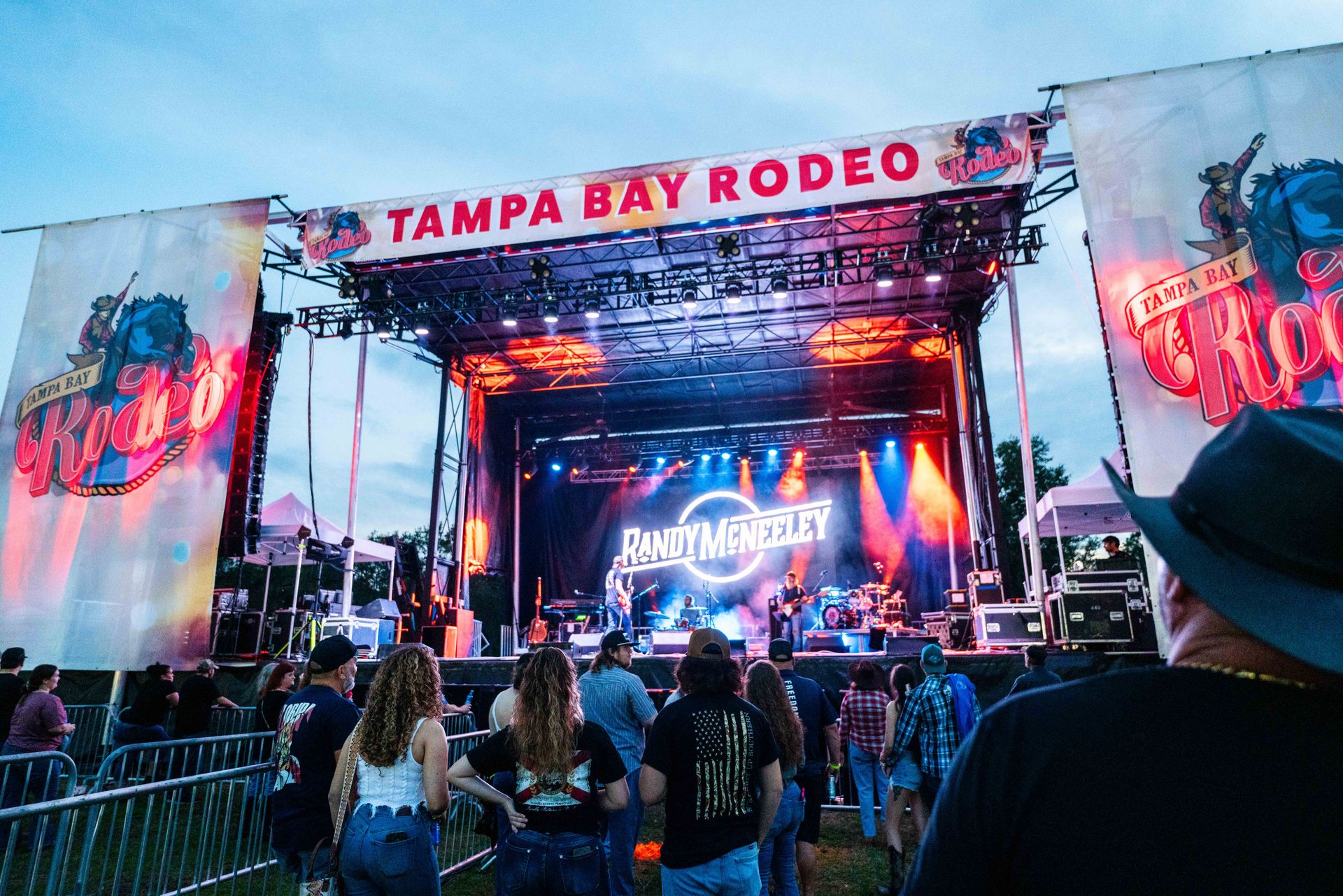 A group of people are standing in front of a stage at tampa bay rodeo.