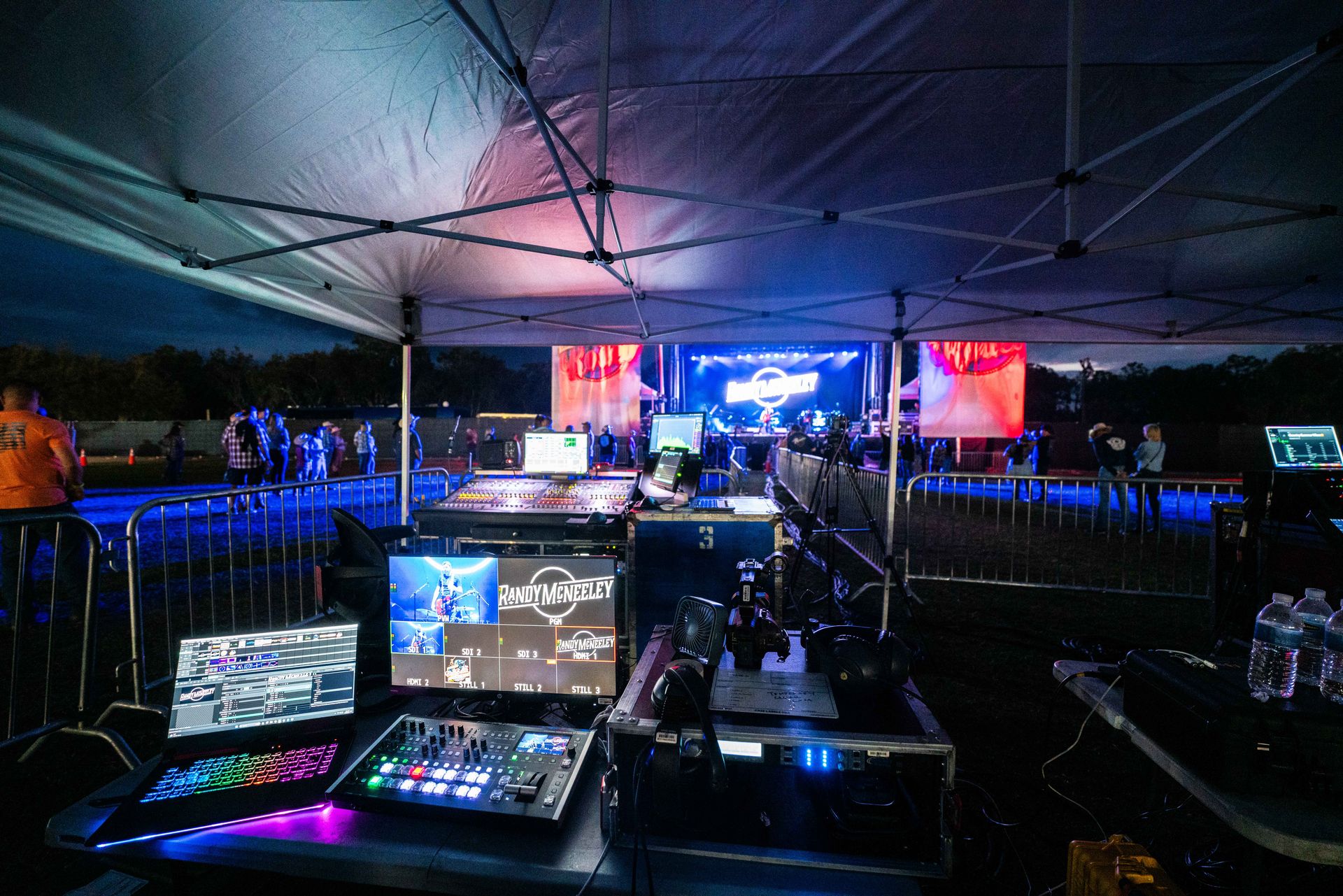 A group of people are standing in front of a stage under a tent.