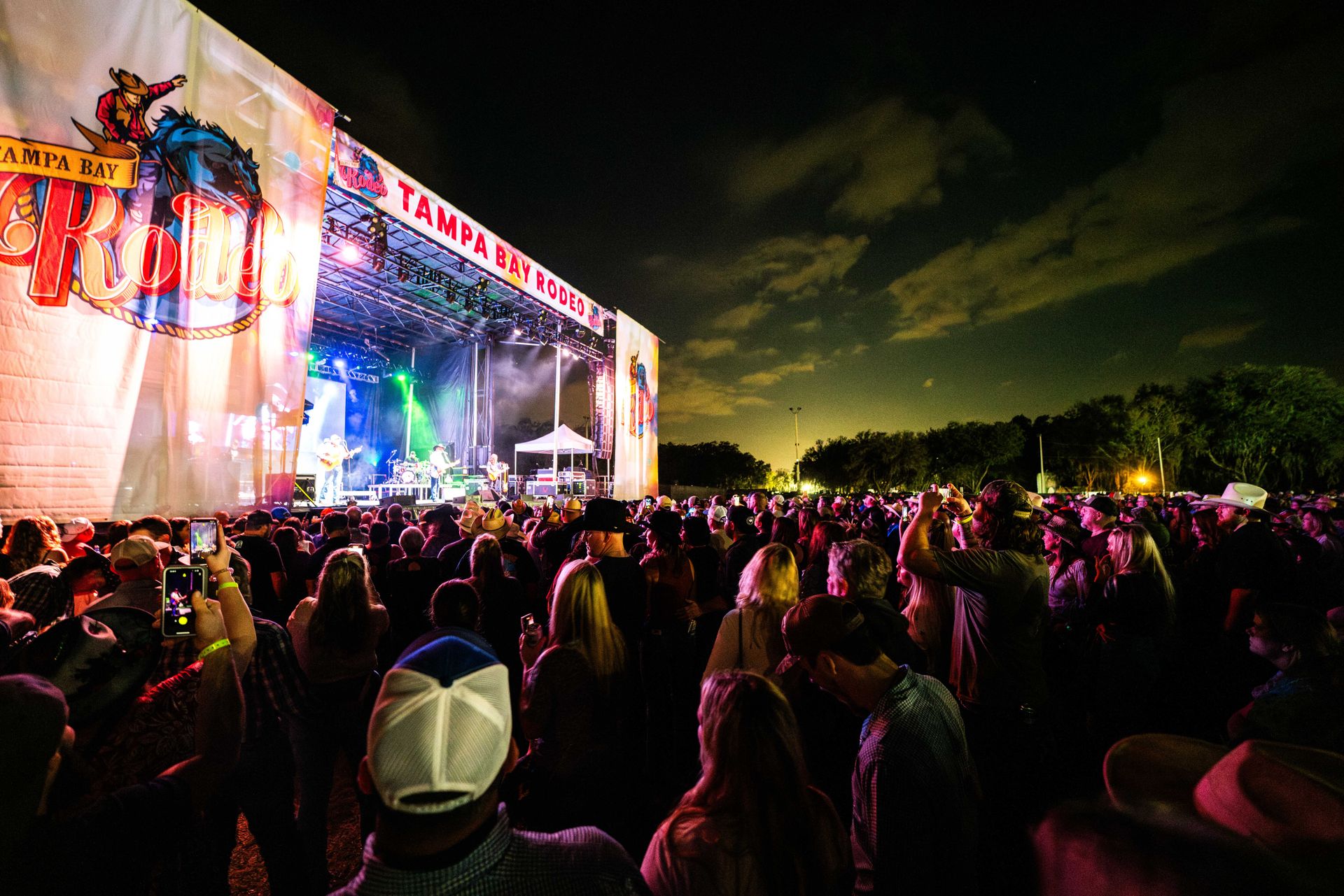 A crowd of people are standing in front of a stage at a concert.