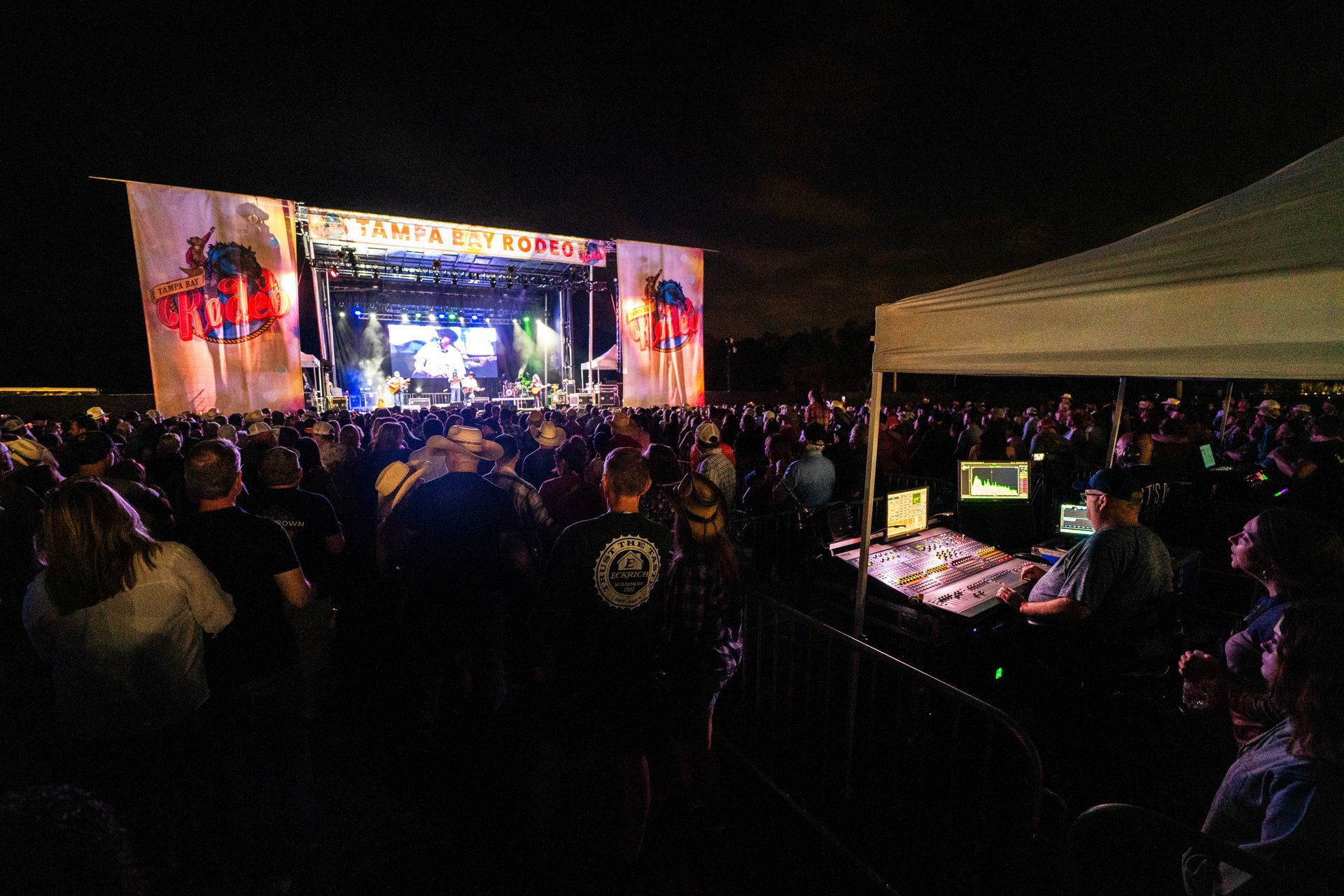 A crowd of people are watching a concert at night.