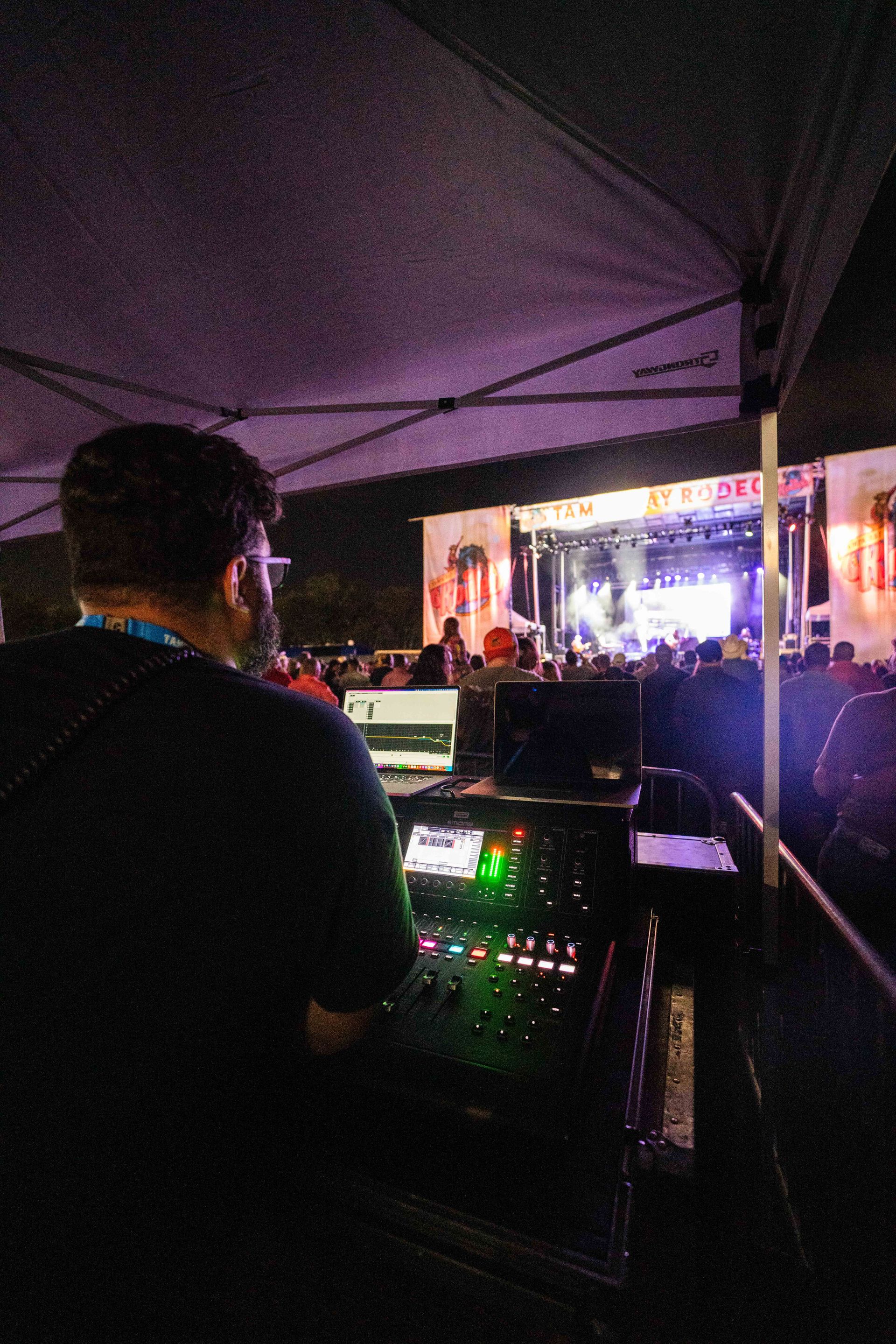 A man is standing in front of a stage at a concert.