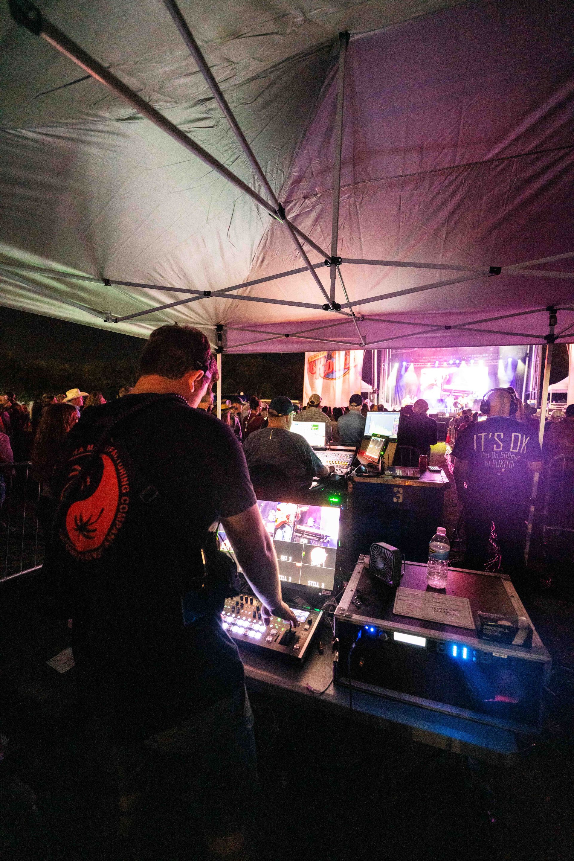 A man is playing a dj set in a tent at a concert.