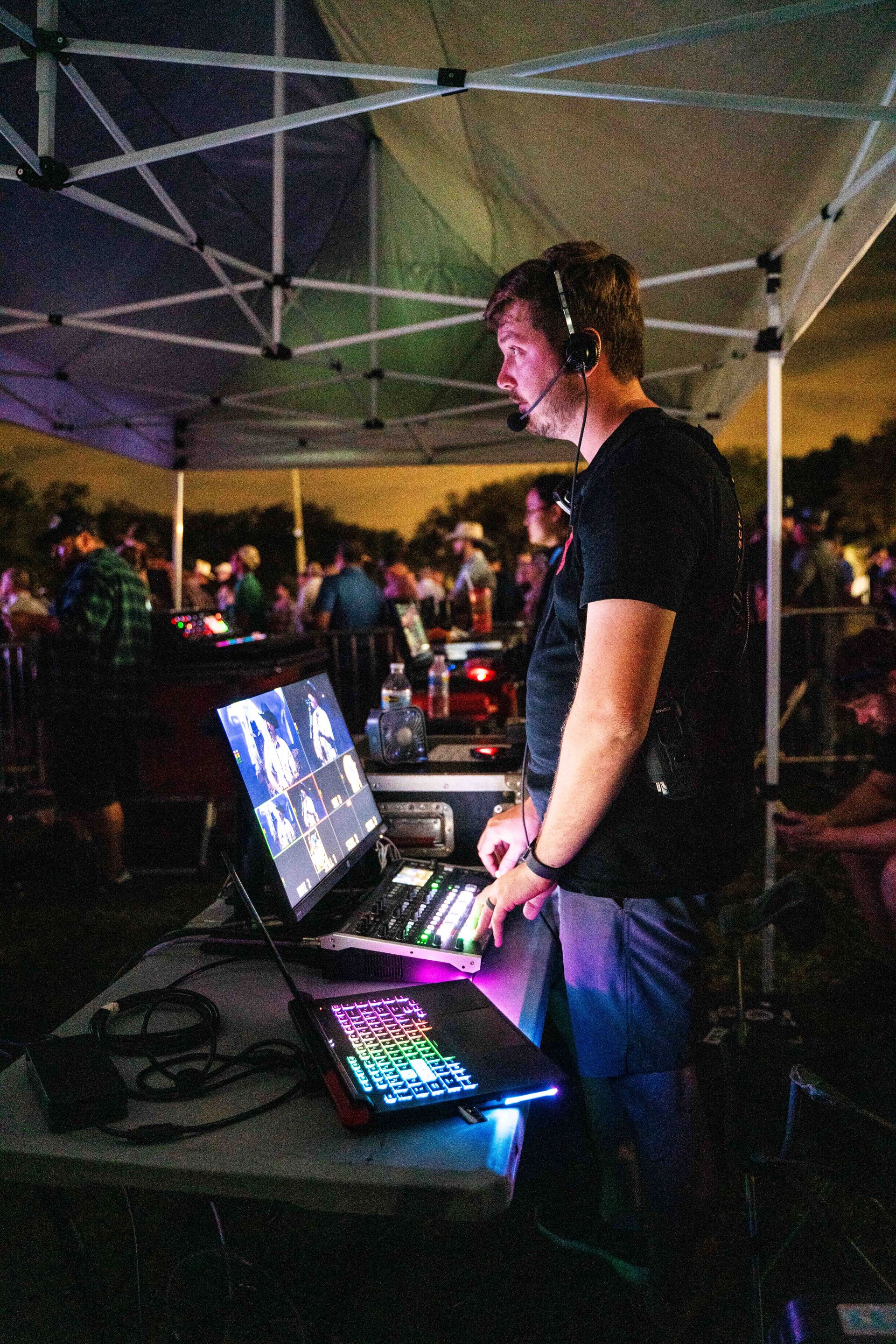 A man wearing headphones is standing in front of a laptop computer.