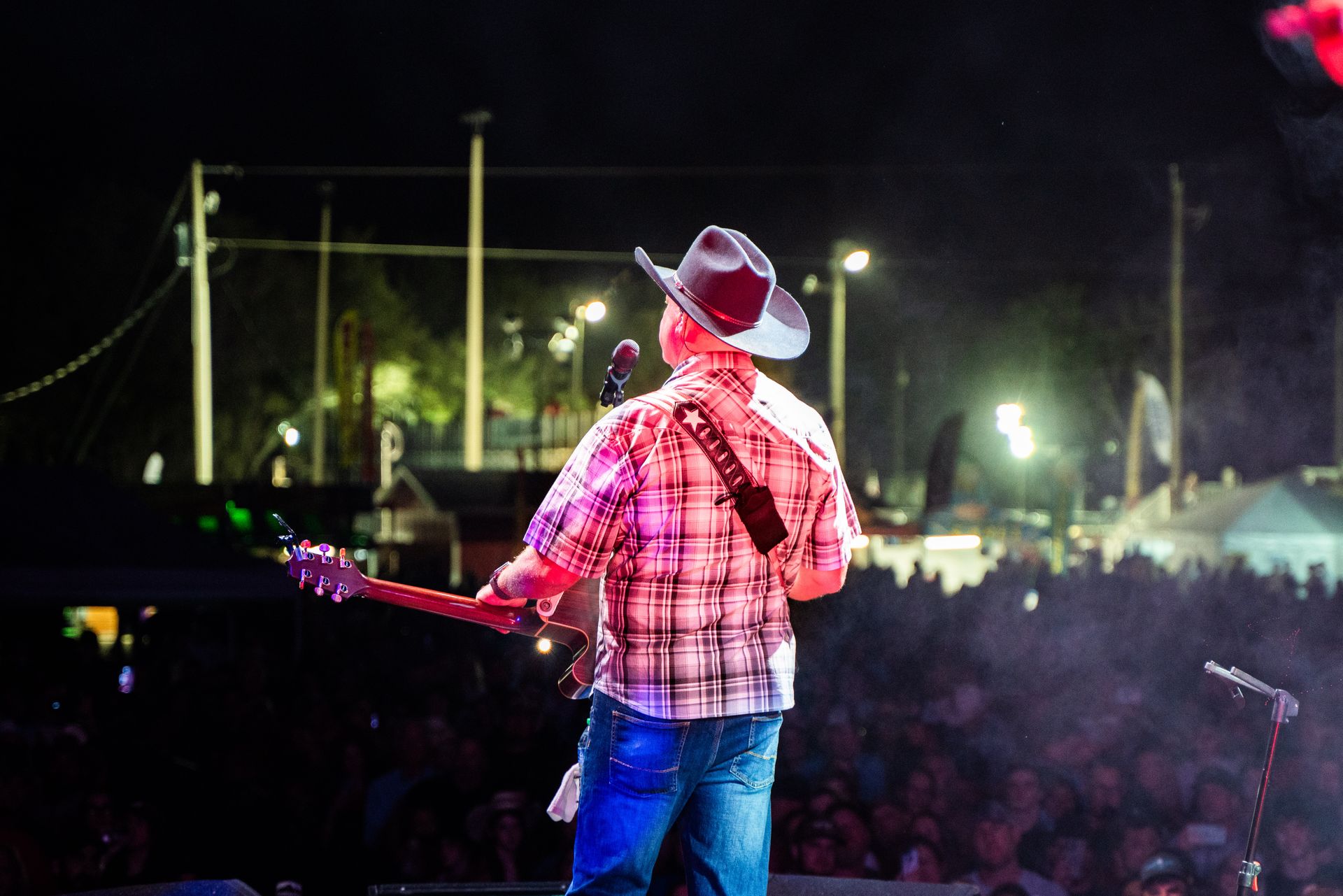 A man in a cowboy hat is playing a guitar on stage in front of a crowd.