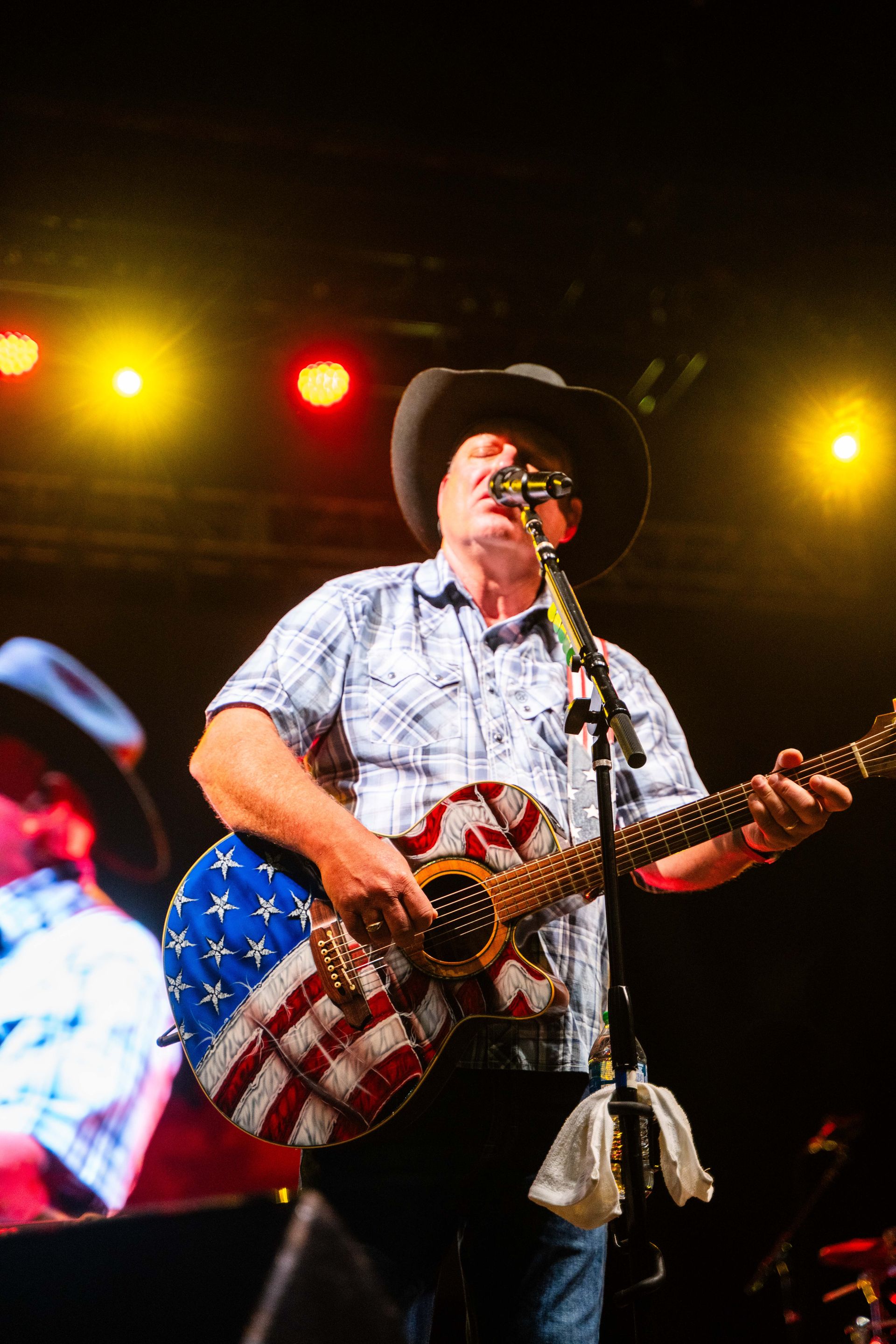 A man is playing a guitar and singing into a microphone on a stage.
