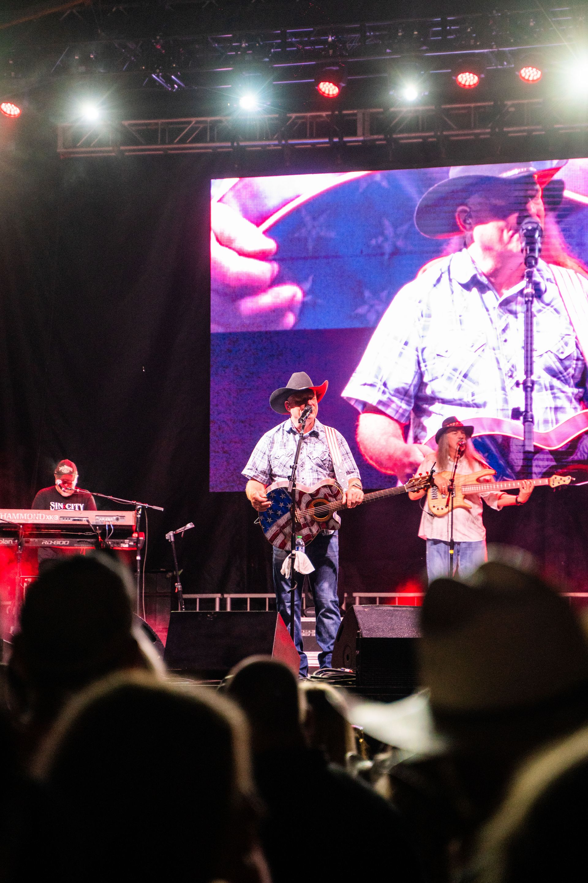 A group of men are playing instruments on a stage in front of a large screen.