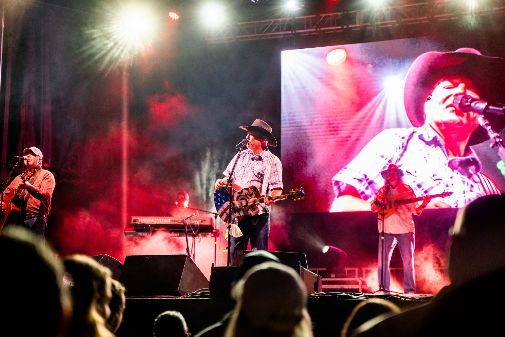 A man in a cowboy hat is singing into a microphone on a stage.
