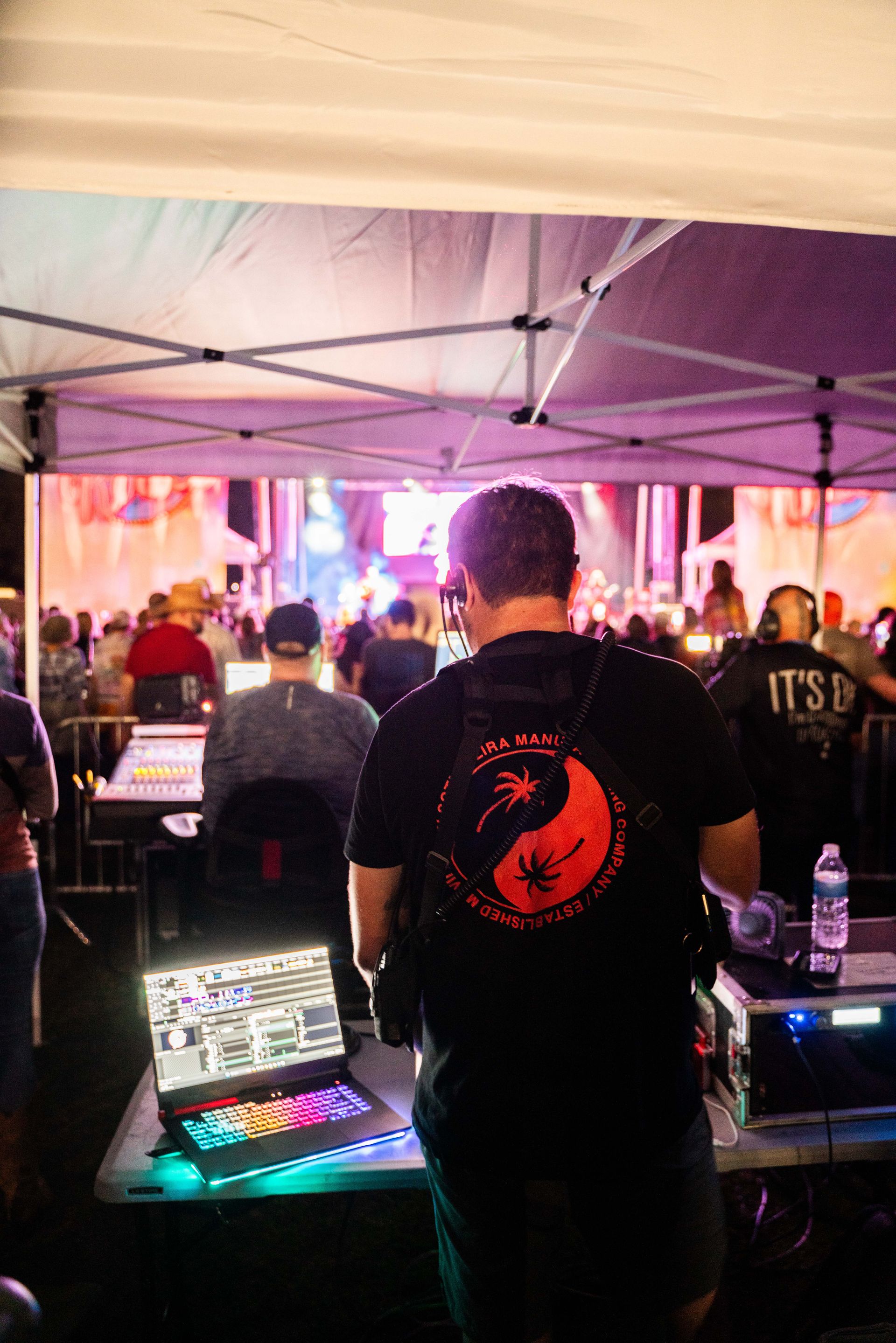 A man is standing in front of a laptop computer in a tent.