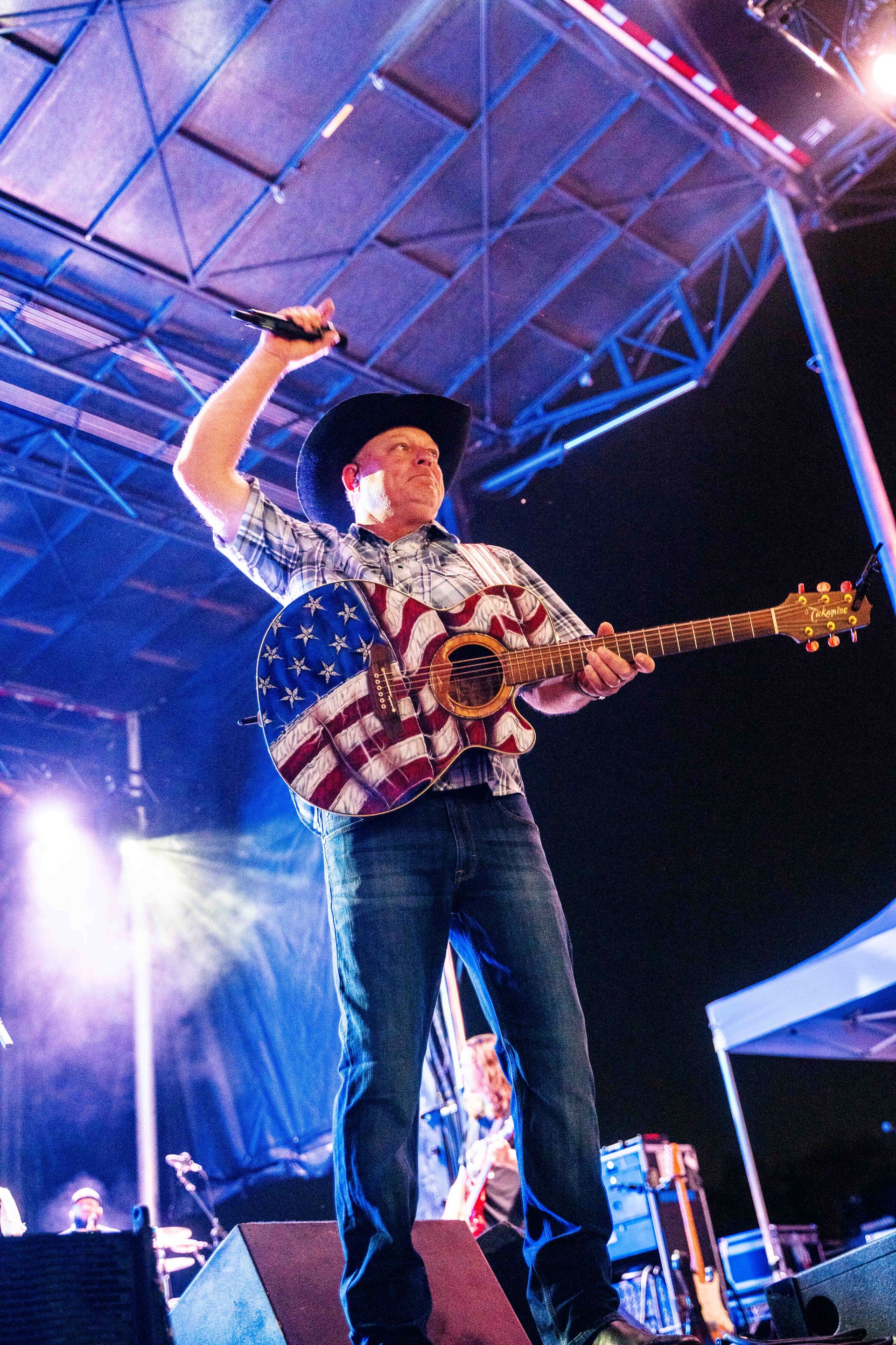 A man is playing a guitar and singing into a microphone on a stage.