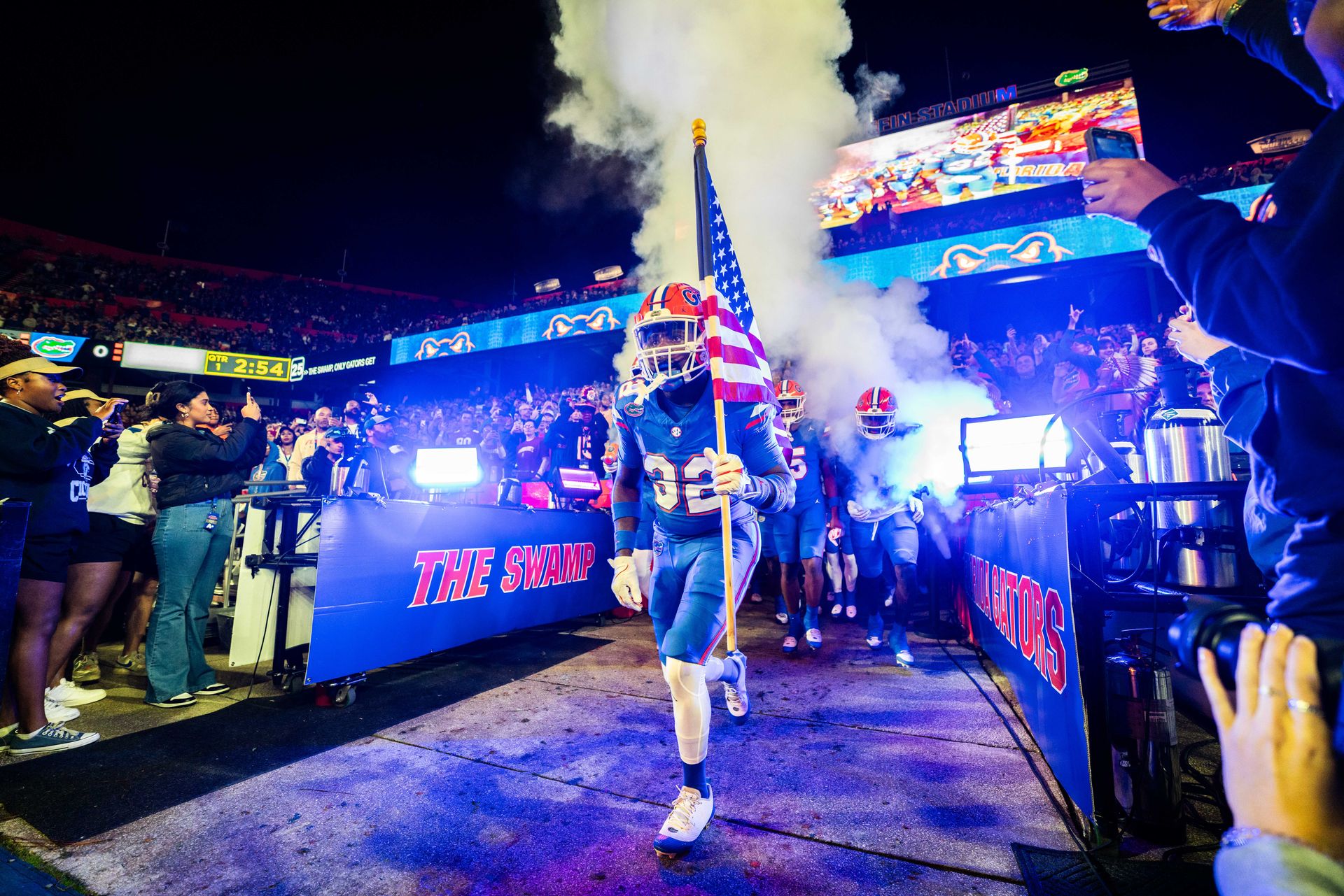 A football player is walking through a tunnel with smoke coming out of it.