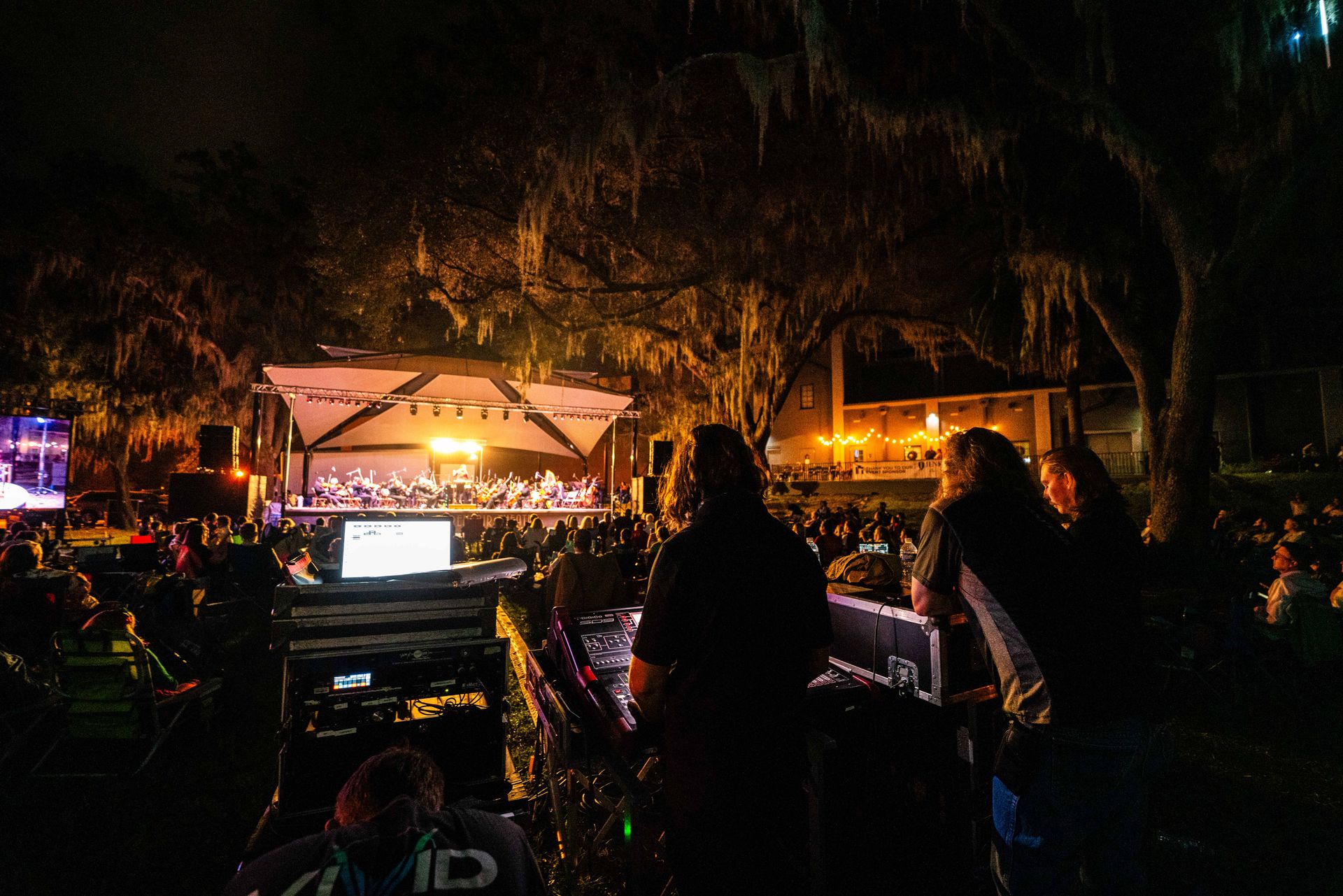 A group of people are standing in front of a stage at night.