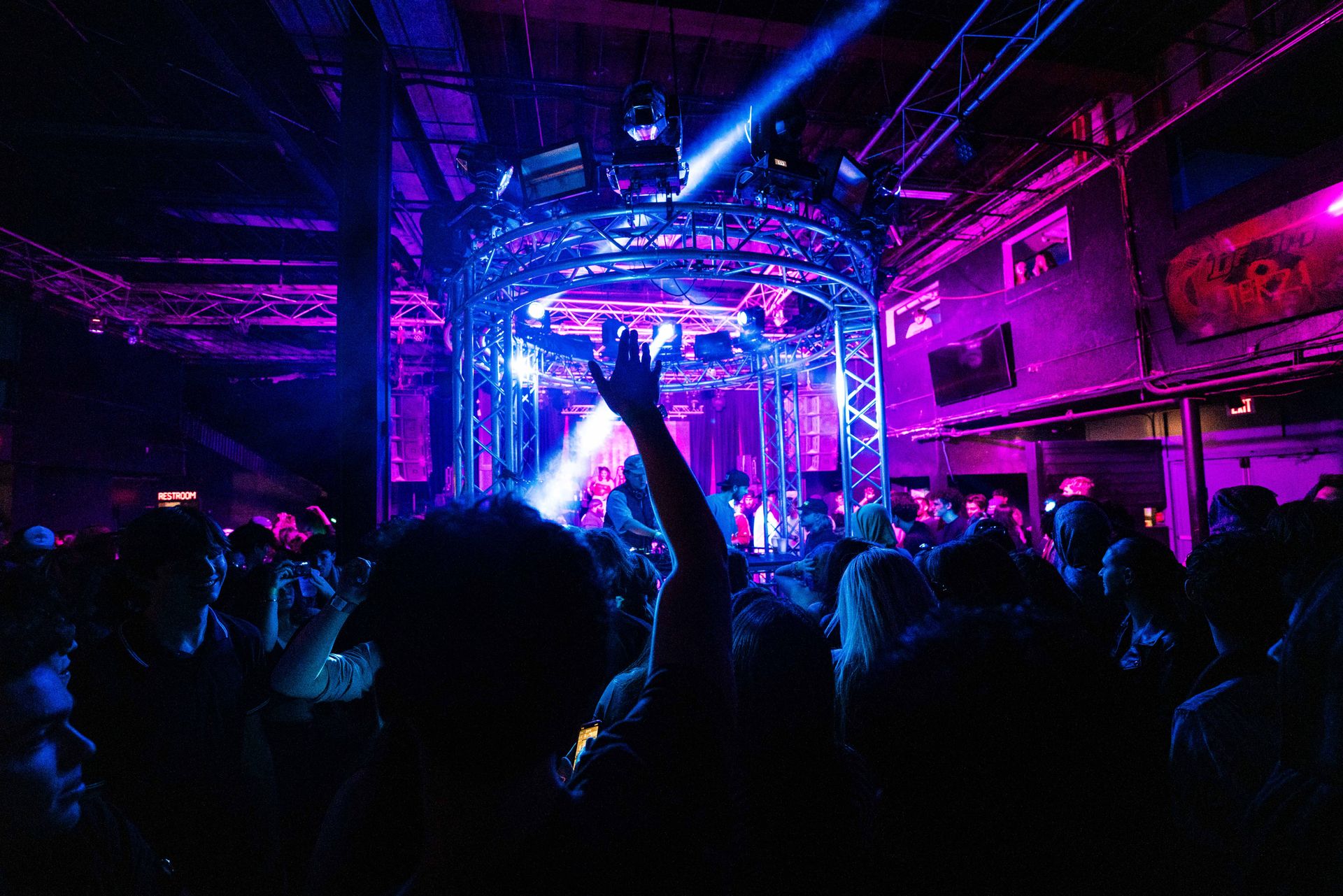 A crowd of people are dancing in a club with purple lights.