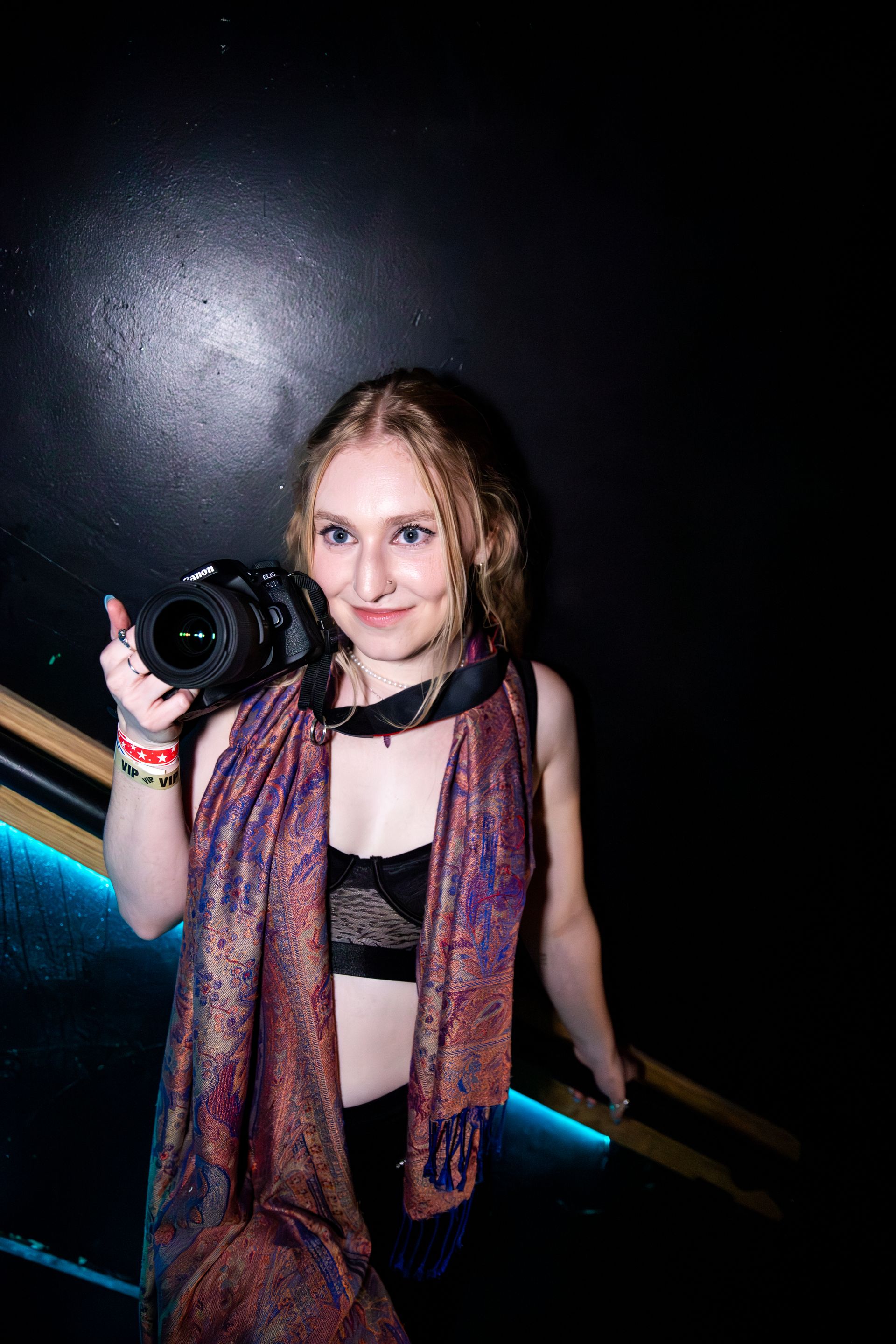 A woman is holding a camera in her hand in a dark room.