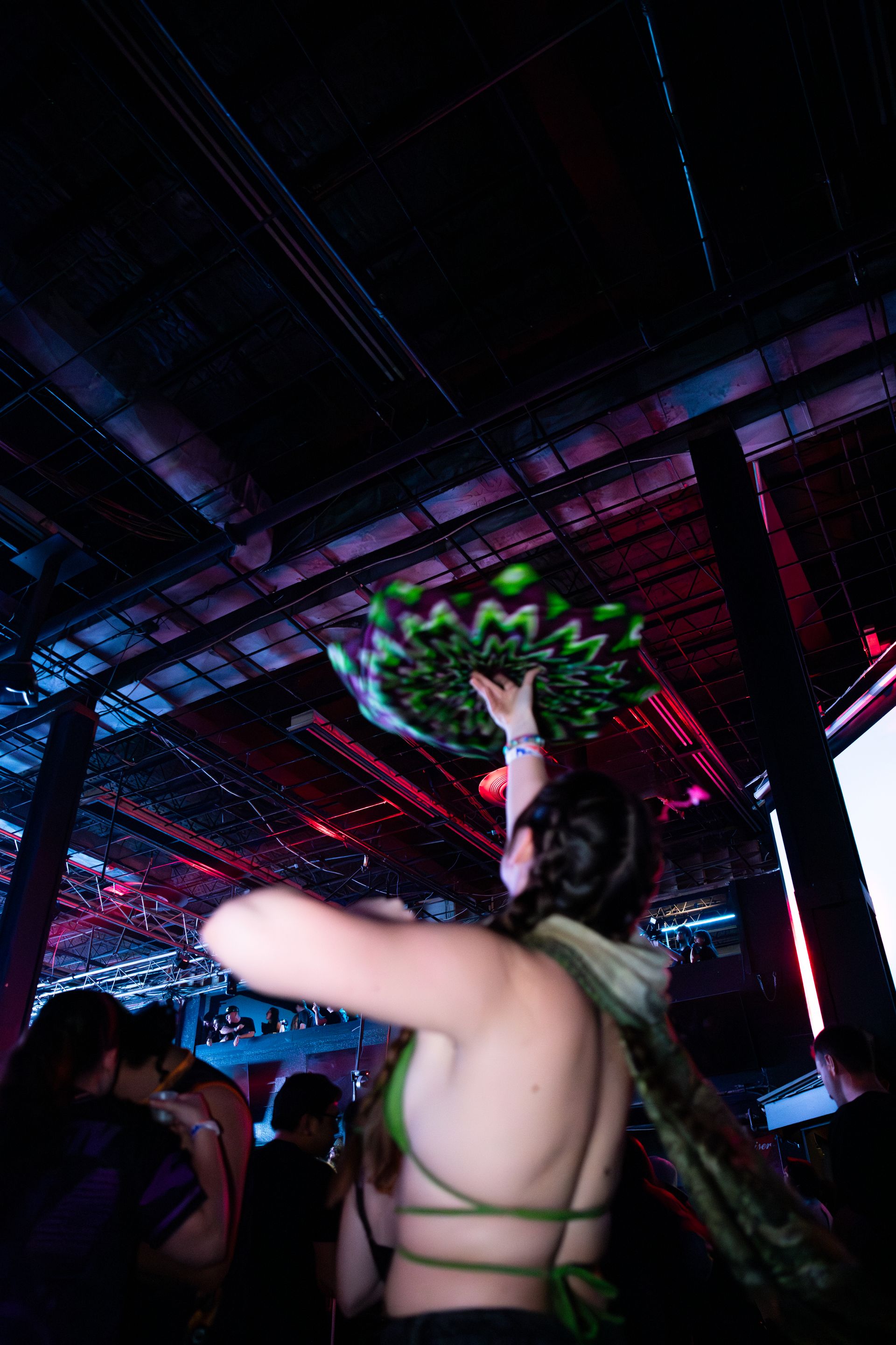 A woman is holding a bunch of green bottles in her hand in a dark room.